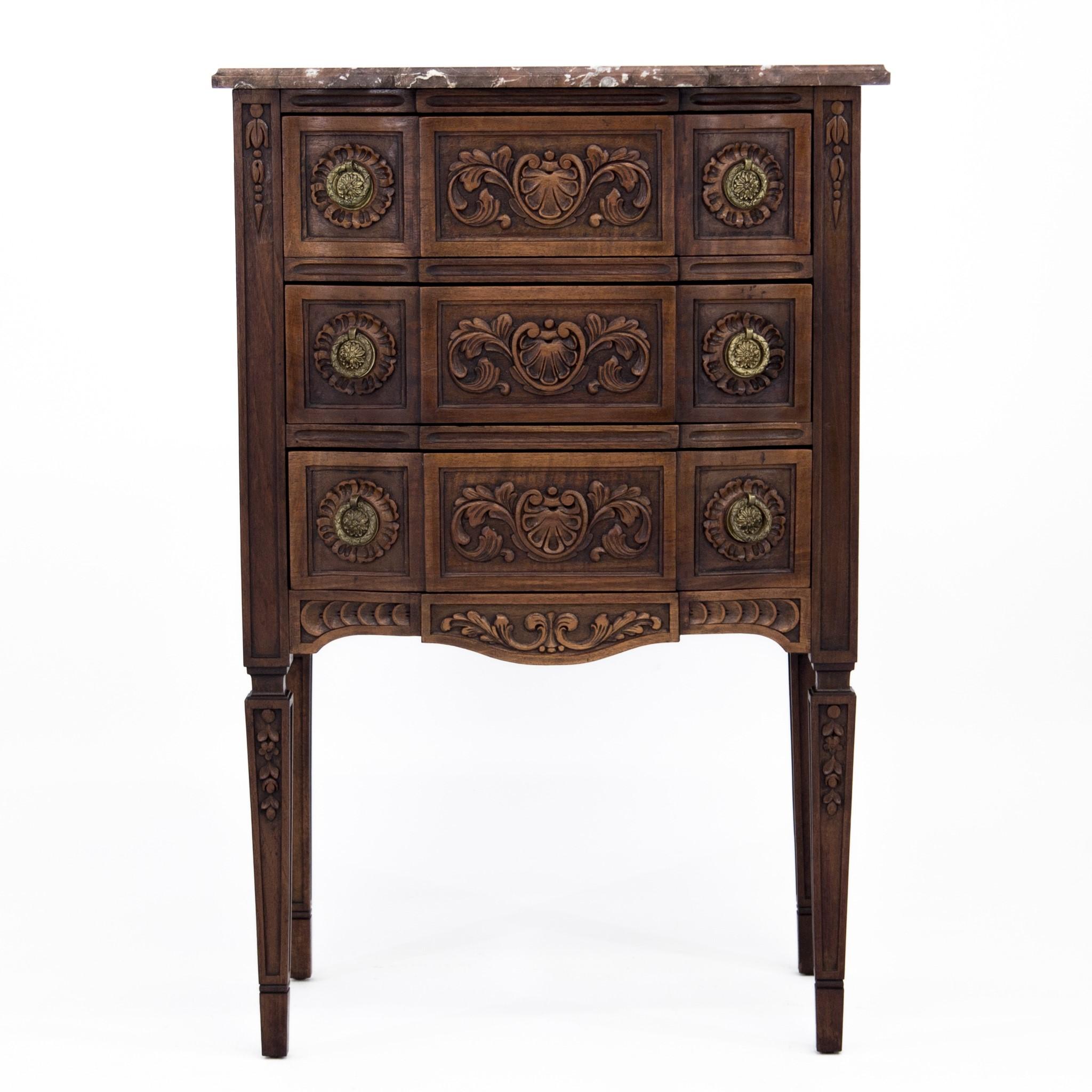 Late 19th century carved Louis XVI style three-drawer commode, bedside table, nightstand or side table with shaped marble top and Empire style brass ring pulls, made in Belgium. The drawer fronts, apron and legs have intricate carved foliate design.