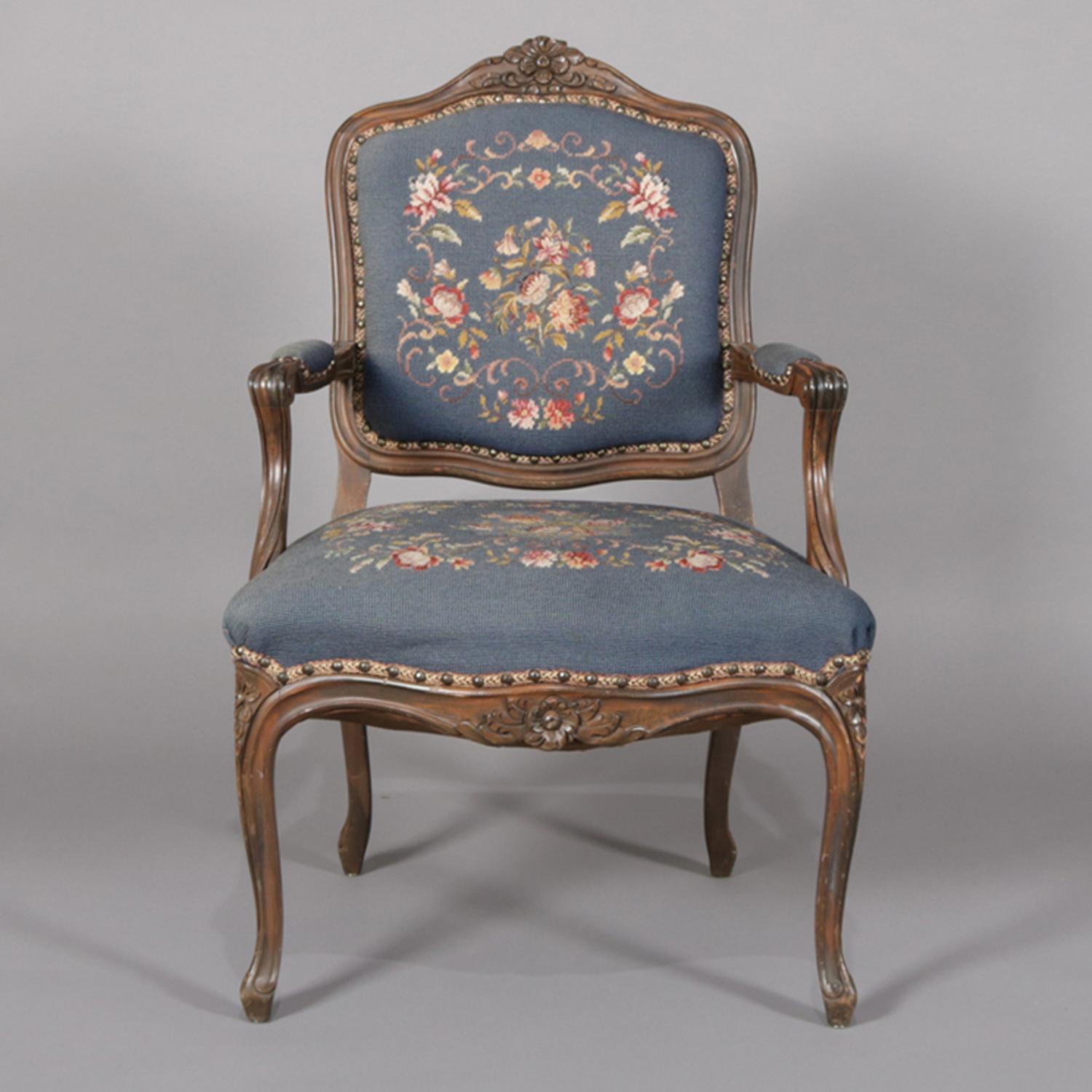 A French Louis XVI style armchair features walnut frame with floral and foliate carved crest, skirt and legs, floral needlepoint upholstered seat, back and arm, raised on cabriole legs, circa 1950.

Measures: 38