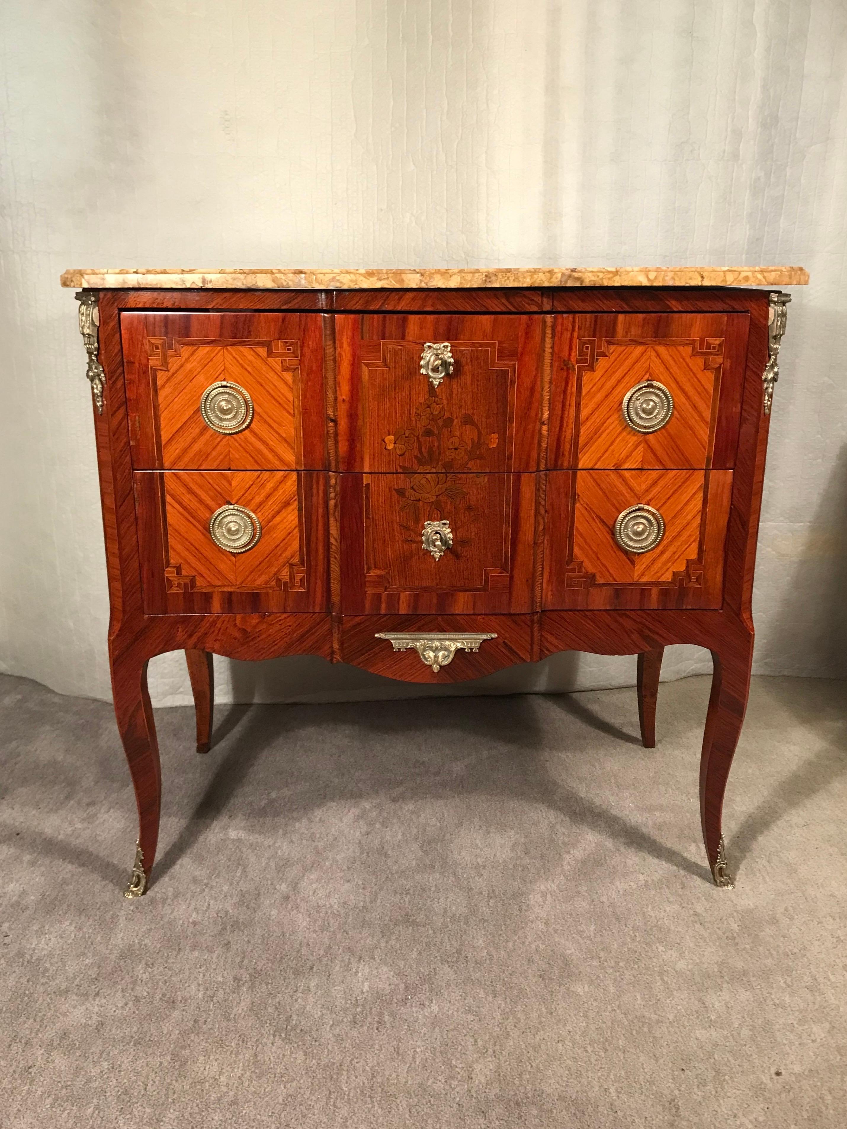 Explore the timeless elegance of a late 18th-century French Louis XVI chest of drawers. This exquisite piece stands gracefully on slender cabriole legs and features two drawers adorned with beautiful kingwood veneer and flower marquetry decor sans