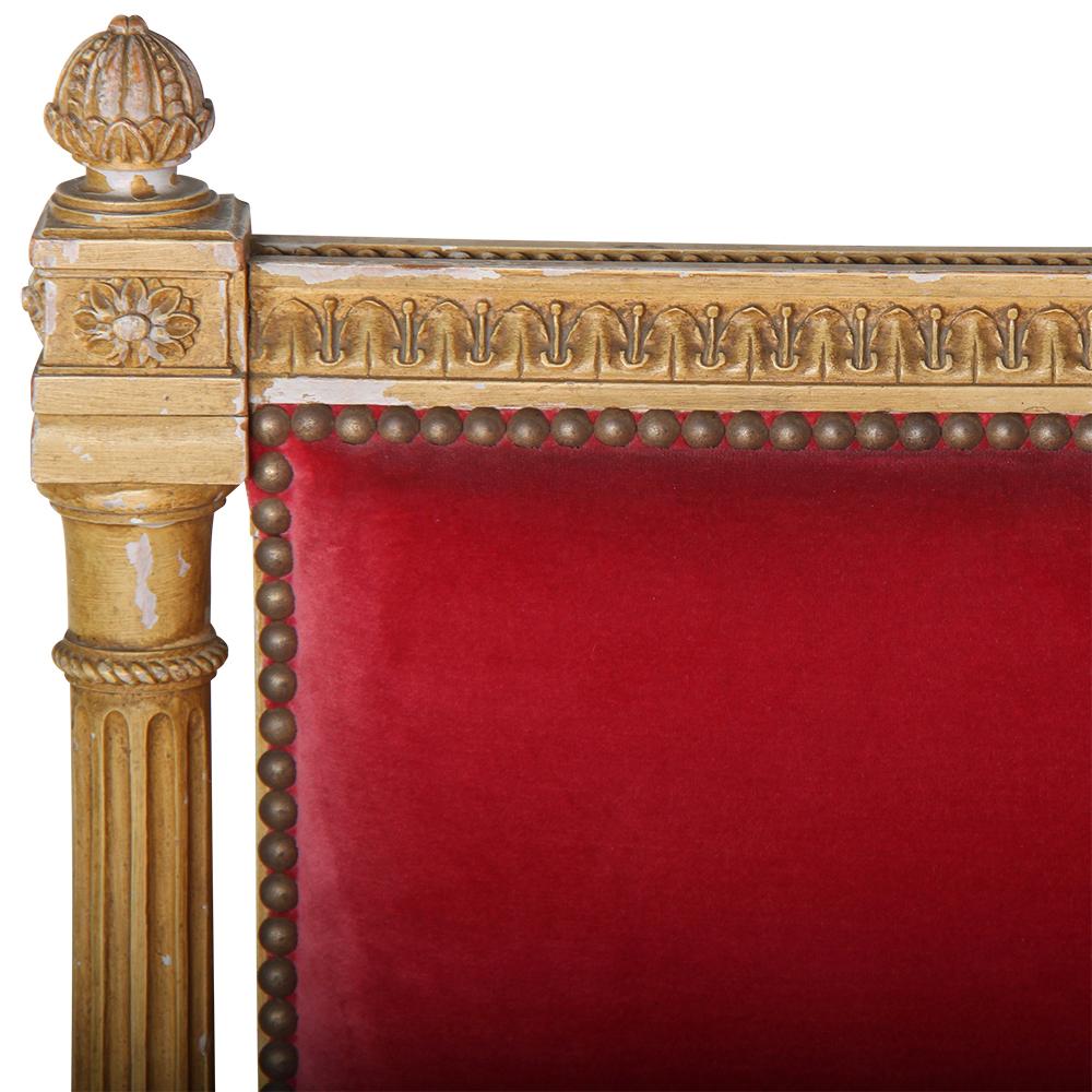 A French carved and painted Louis XVI style daybed, the beechwood frame hand carved with fine classical details and with carved and fluted legs and columns to each side.
Upholstered in muted red velvet, with a loose down-filled seat cushion and