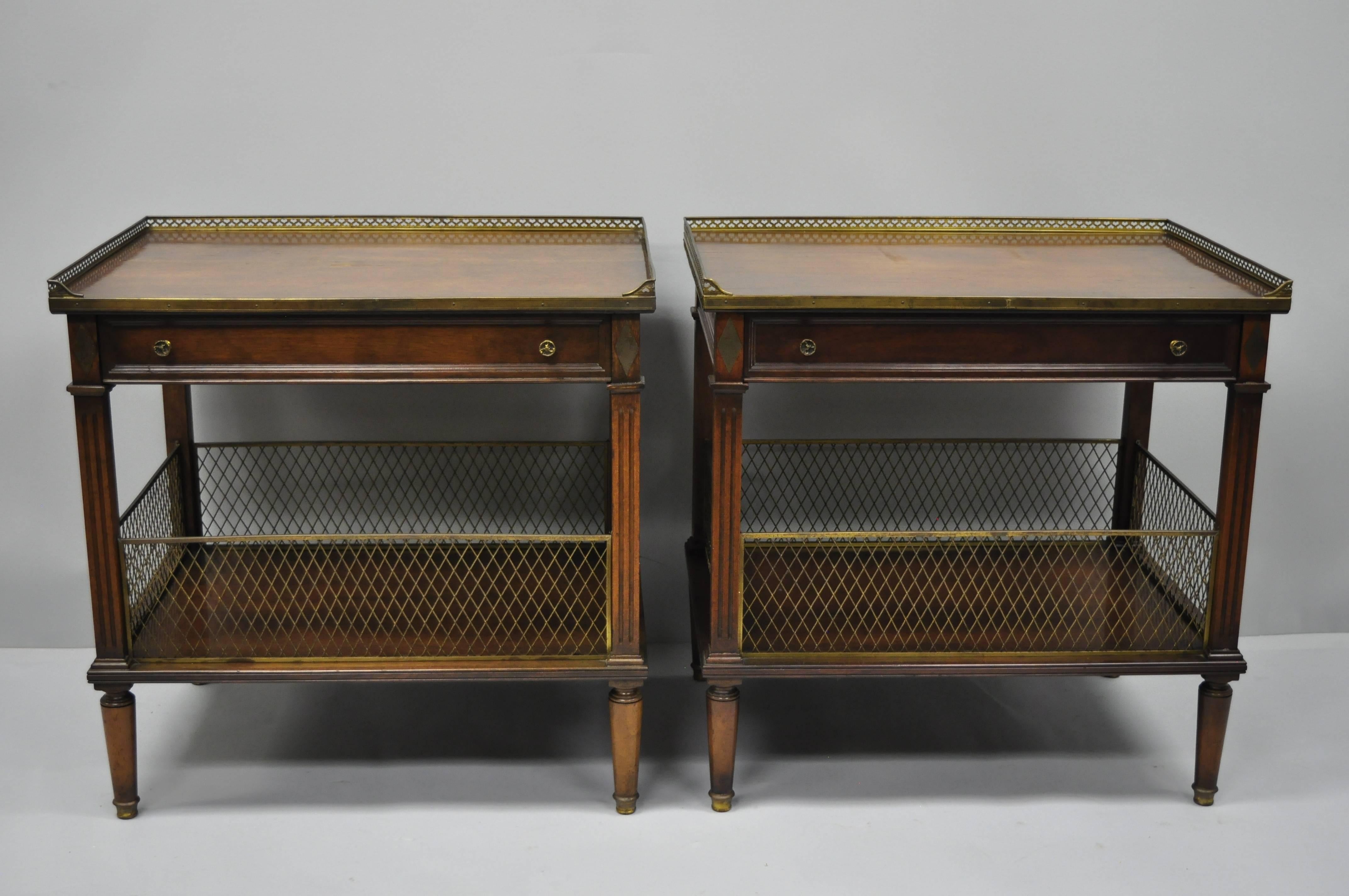 Pair of vintage French Louis XVI / Maison Jansen style oversize walnut end tables. Item features full brass gallery/basket to lower shelf, brass gallery to top tier, inlaid brass diamond ormolu to corners, finished back, one dovetailed drawer,