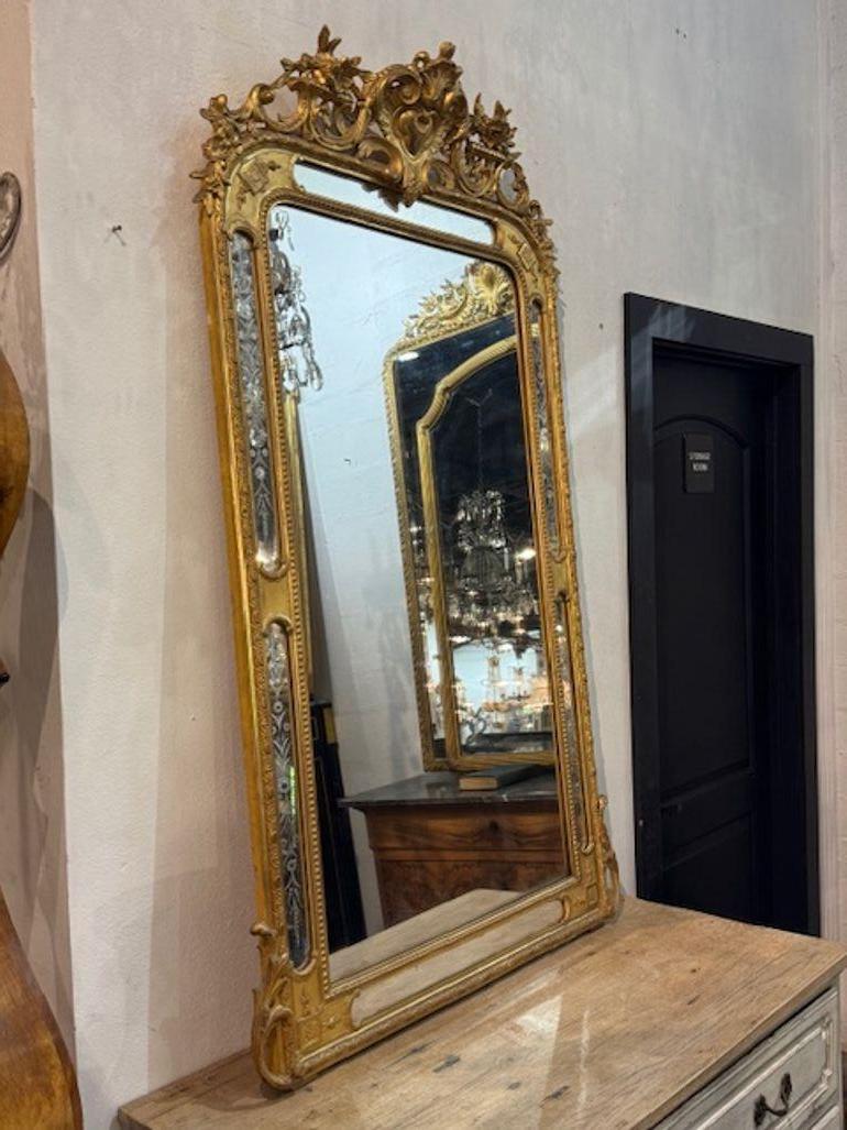 Fino espejo francés Luis XVI del siglo XIX de madera dorada y cristal grabado. Estás explorando un espejo que es tanto una obra de arte como un reflejo: un espejo francés Luis XVI del siglo XIX de madera dorada y cristal grabado que combina la
