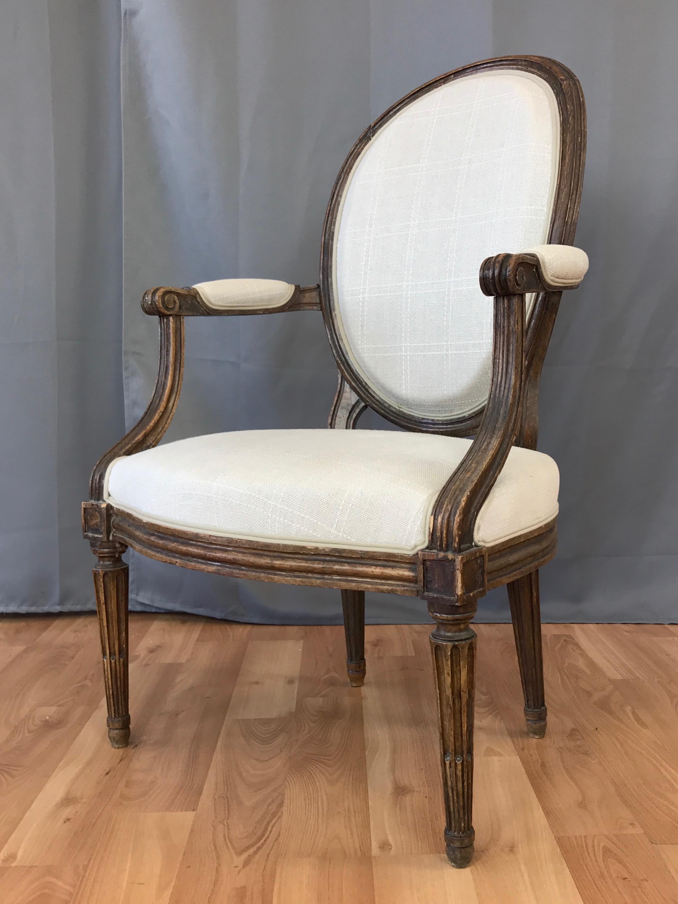 A Louis XVI fauteuil-style armchair in beech and linen by notable French master furniture maker Martin Jullien, circa 1760s.

Balloon back rises above shaped seat flanked by cabriolet scroll arms. Stands on fluted and turned legs, the back pair
