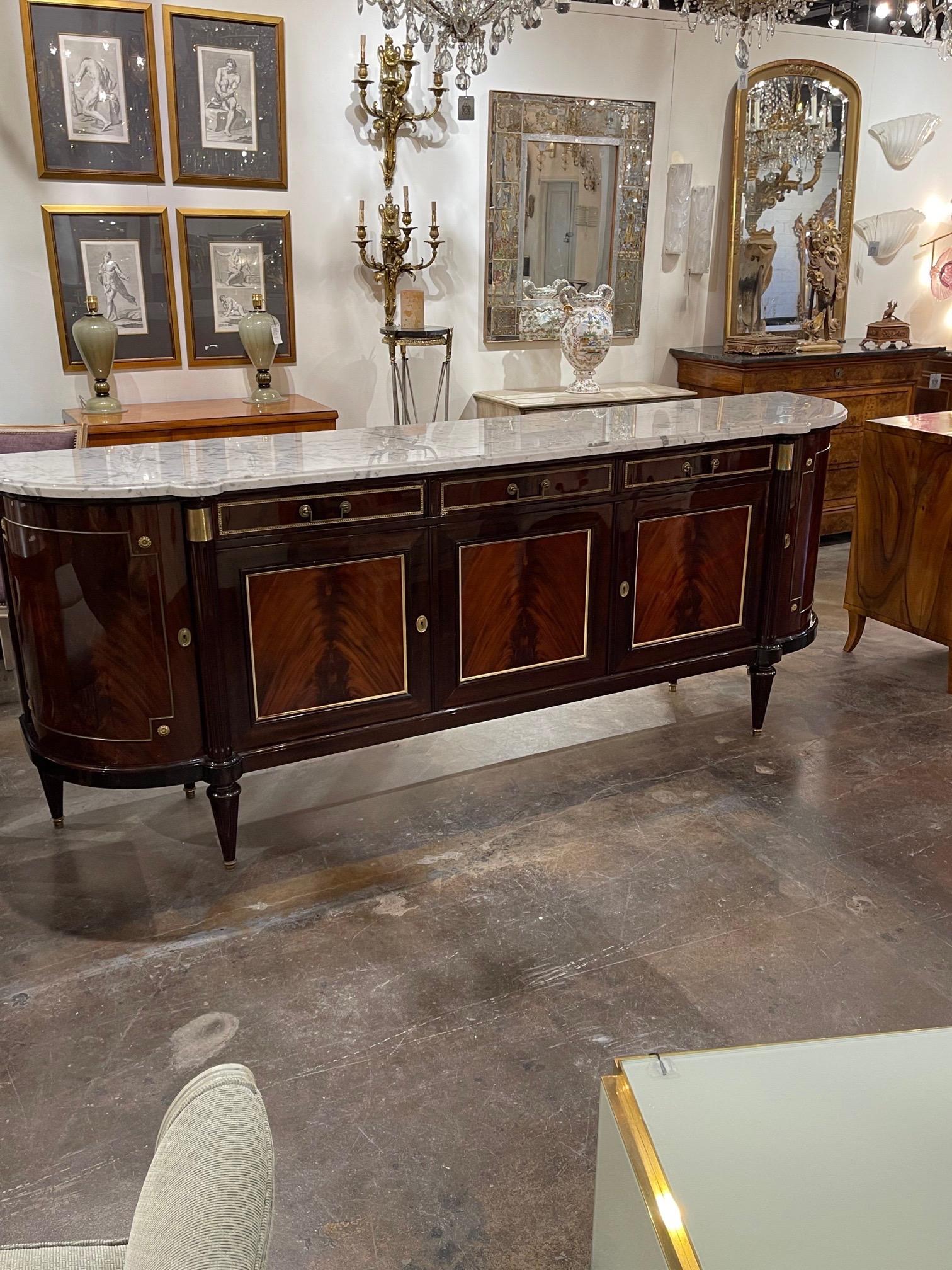 Exceptional French Louis XVI flame mahogany sideboard. The piece has a gorgeous Carrara marble top and decorative brass mounts. So elegant with tons of storage. Amazing!!