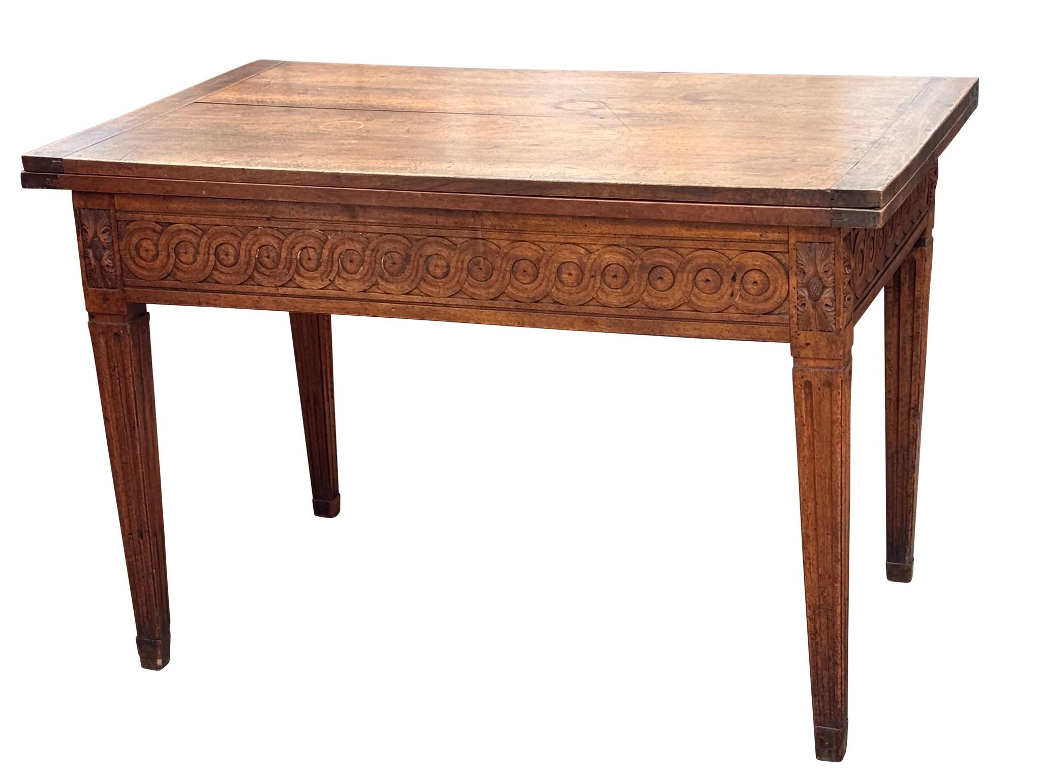 French Louis XVI folding table, late 18th century, walnut.  The top unfolds to reveal two integrated leaves, expanding the form from console to dining. Carved guilloche frieze, fluted legs, and rosette corners. A well-executed example of functional