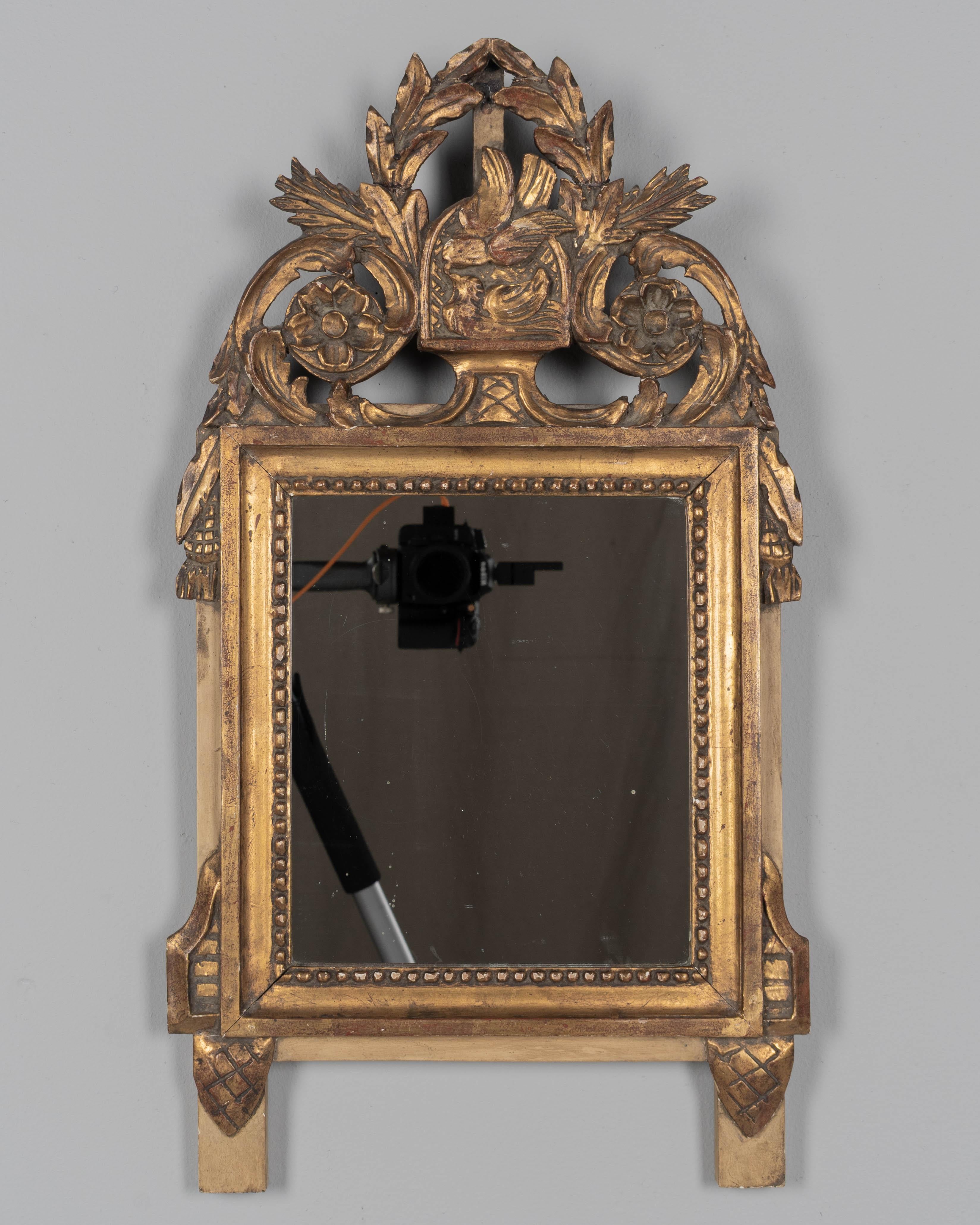 Miroir de mariage en bois doré, de style Louis XVI, en parcellaire provençal français, du début du XXe siècle. Cimier sculpté à la main représentant un couple d'amoureux flanqué d'un tourbillon de guirlandes avec des rosettes et des glands qui