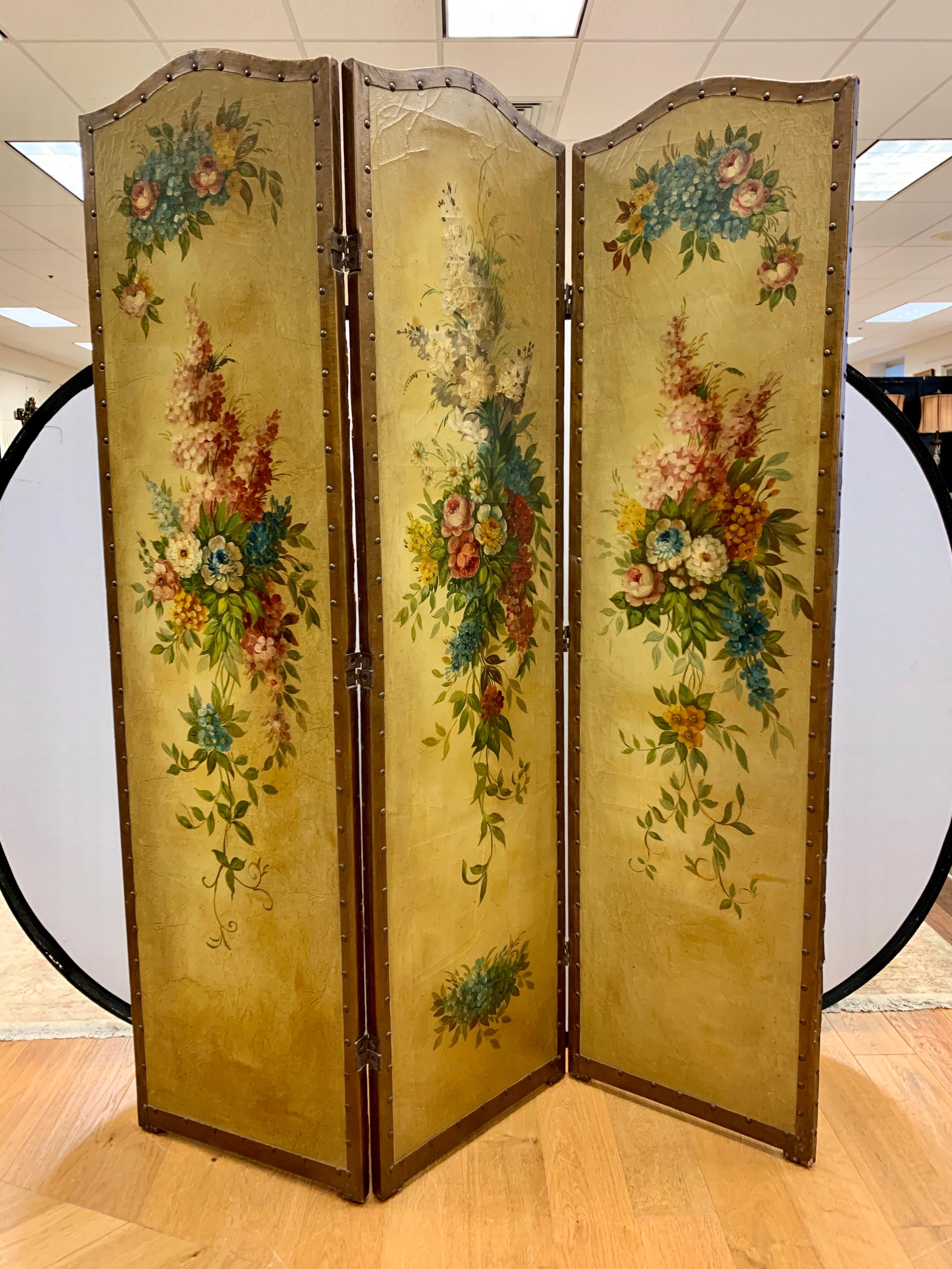A very decorative French Louis XVI three panel painted screen. The three painted panels are bordered by antique nails over leather trim and are nothing short of magnificent. The whole screen is hand painted showing a large cascading floral scene on