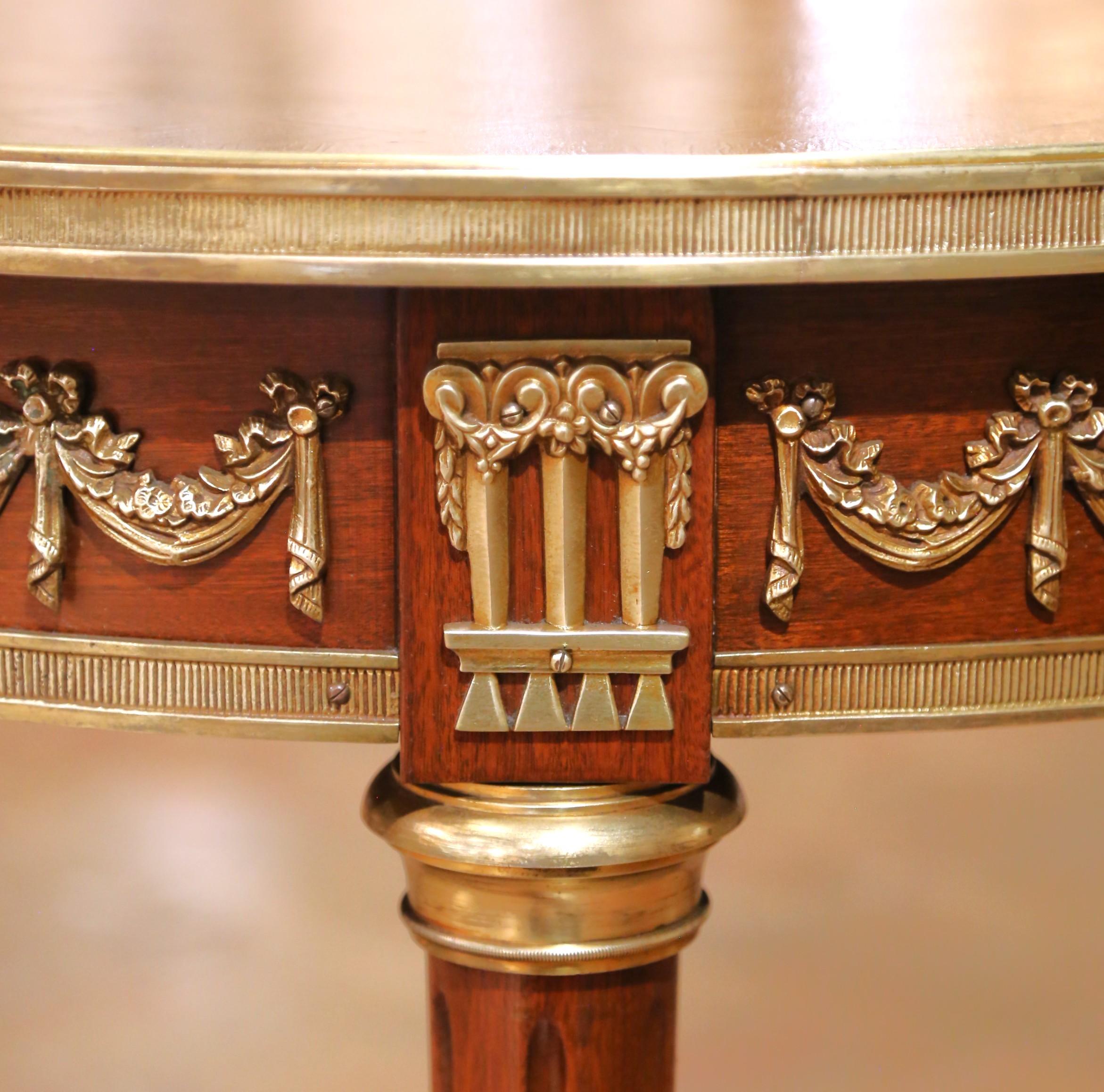 Fabriqué en France vers 1930, cet élégant guéridon du début du XXe siècle est conçu dans le style Louis XVI et présente un plateau rond en acajou avec une marqueterie finement exécutée dans un motif rayonnant. La surface est entourée d'une délicate