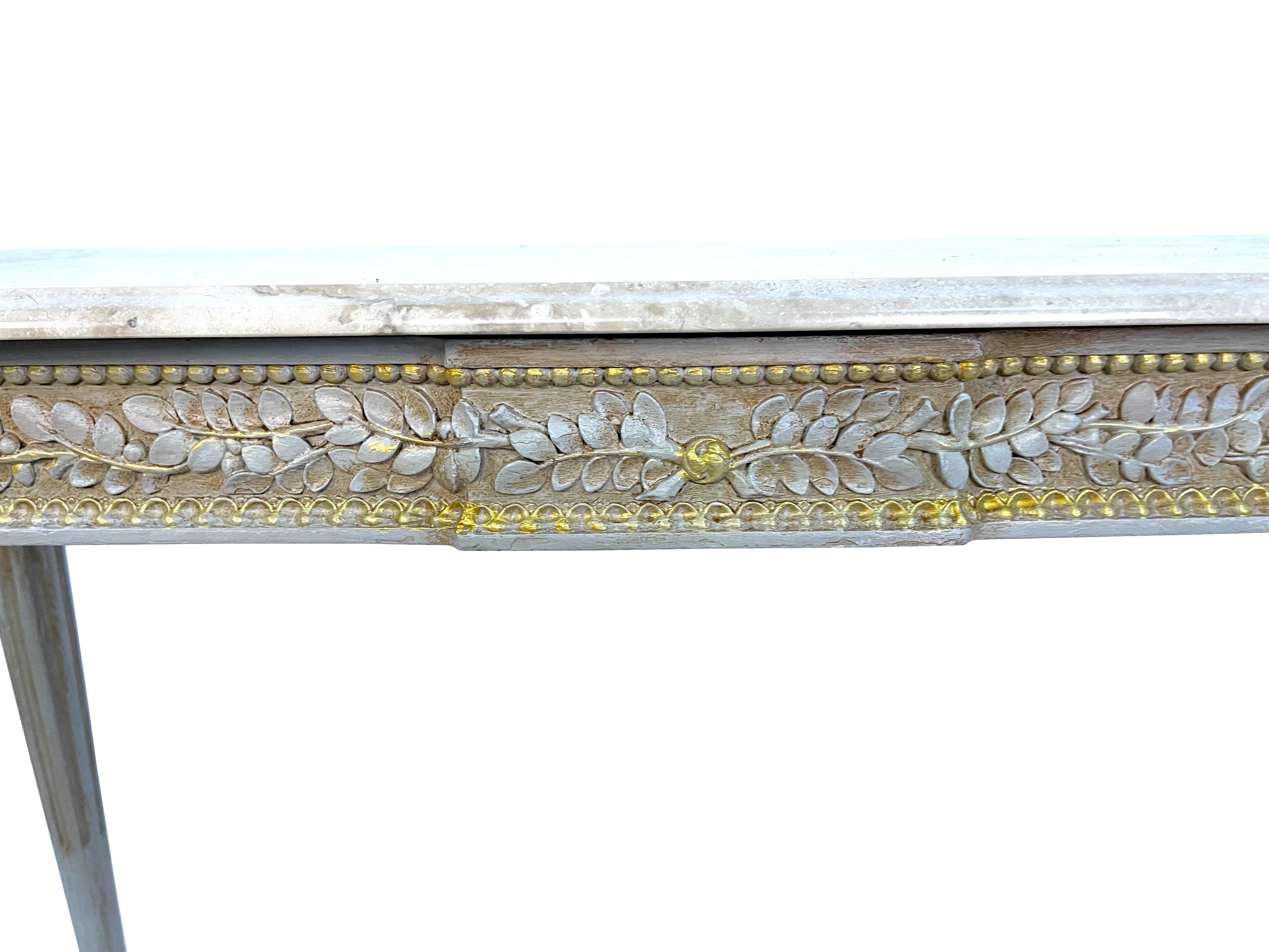 French Louis XVI Maison Jansen beige and gold gilt painted console table intricately carved with foliate detail and beaded edging. Original to the Waldorf Towers 1931 opening in New York City. Each with original silvery beige marble tops over a