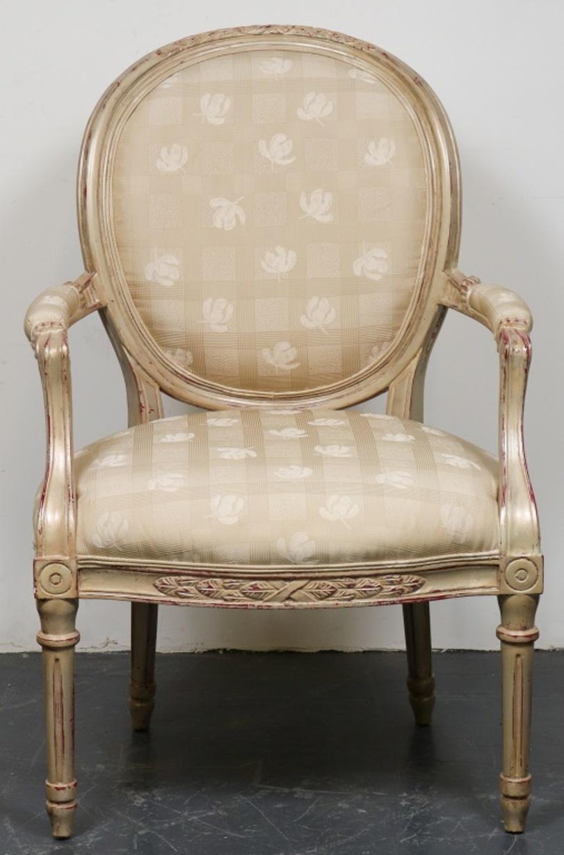 Pair of French Louis XVI manner fauteuils, round backs with painted wood frame and carved foliate detailing, intentionally distressed, with floral over geometric pattern upholstery. 41.75