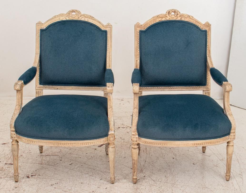Pair of French Louis XVI style white painted carved wood armchairs or 'Fauteuil a la Reine' with blue velvet modern upholstered seats and backs, upon four turned fluted legs. Provenance: Property removed from an Upper East Side townhouse. In