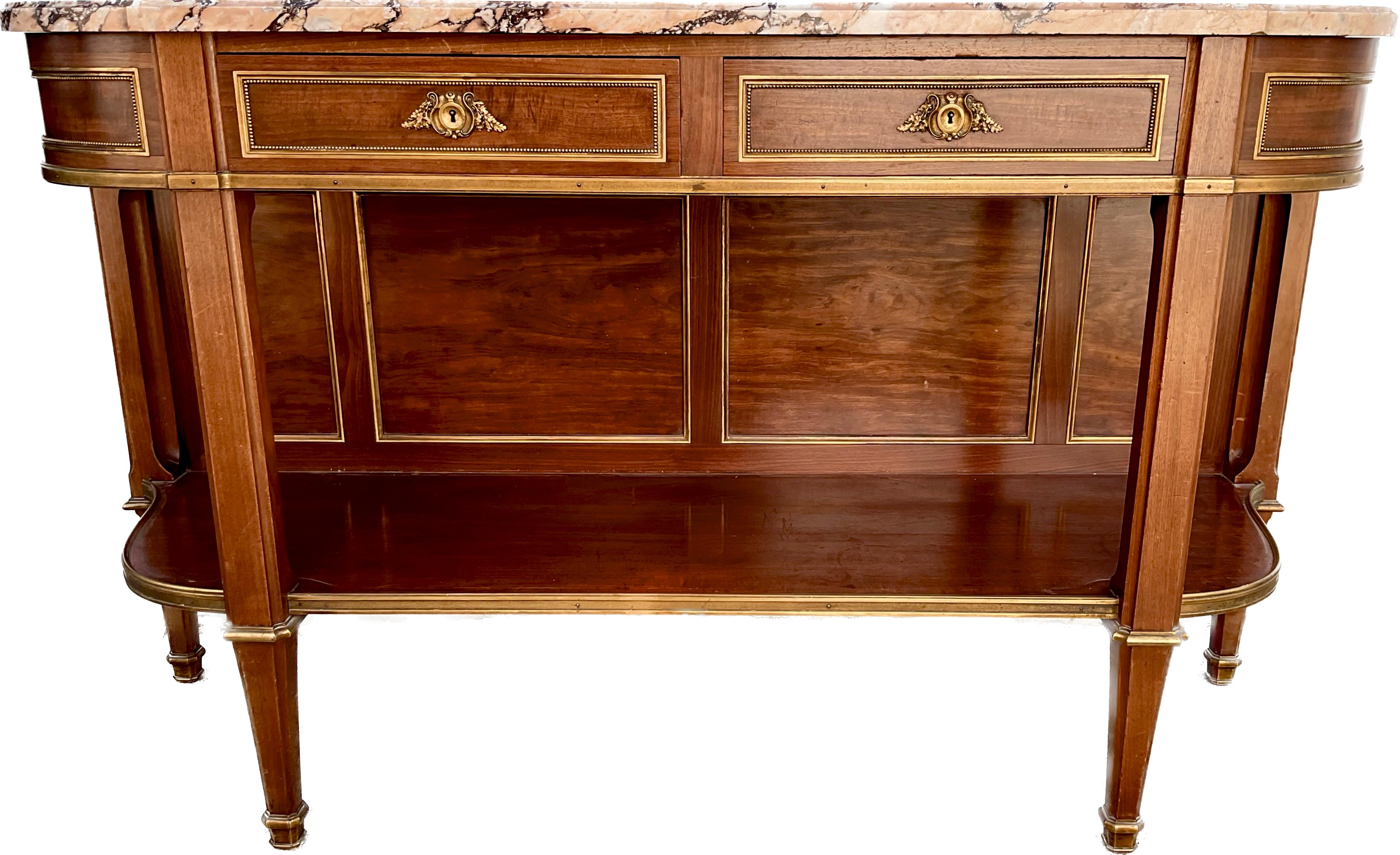 An exquisite French 19th century Louis XVI style mahogany serpentine two drawer open buffet with original Breche Marble top. Bronze ormolu escutcheons and trim all around. Figured mahogany. The buffet is raised on tapered fluted legs with ormolu