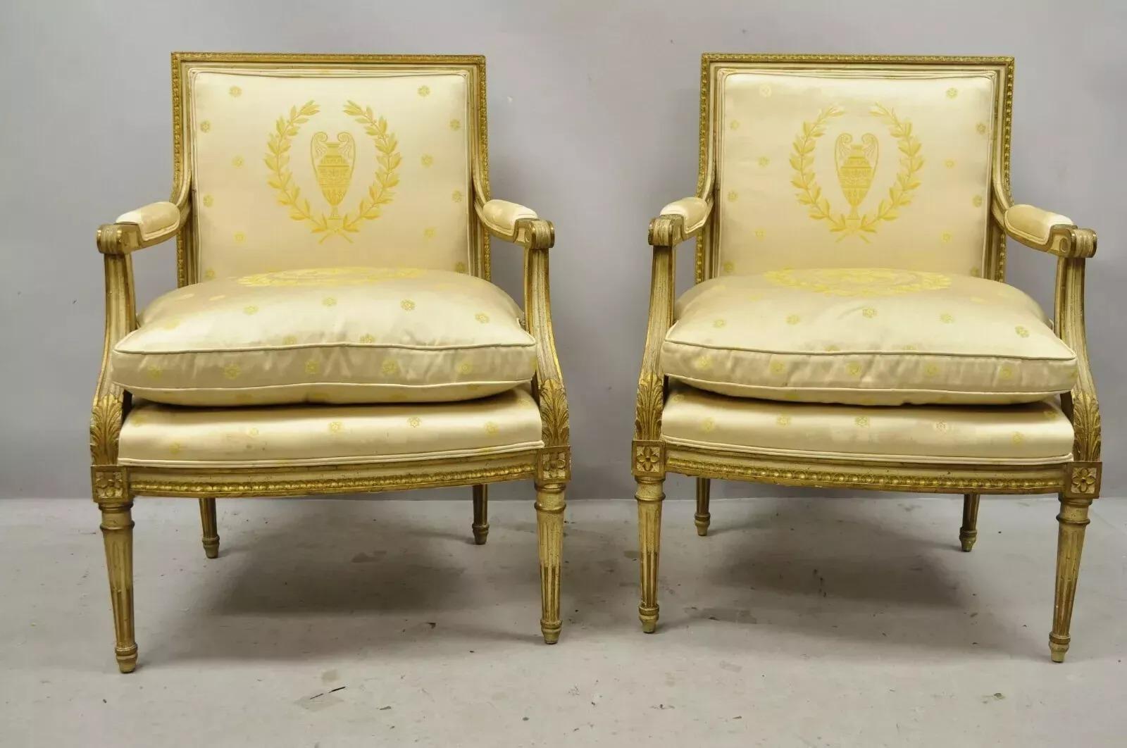 Antique French Louis XVI Neoclassical Style Gold Silk Upholstered Fauteuil Parcel Gilt Arm Chairs - a Pair. Item features original gold silk fabric with urn and wreath pattern, parcel gilt frames, finely carved details. Circa Early 20th Century.