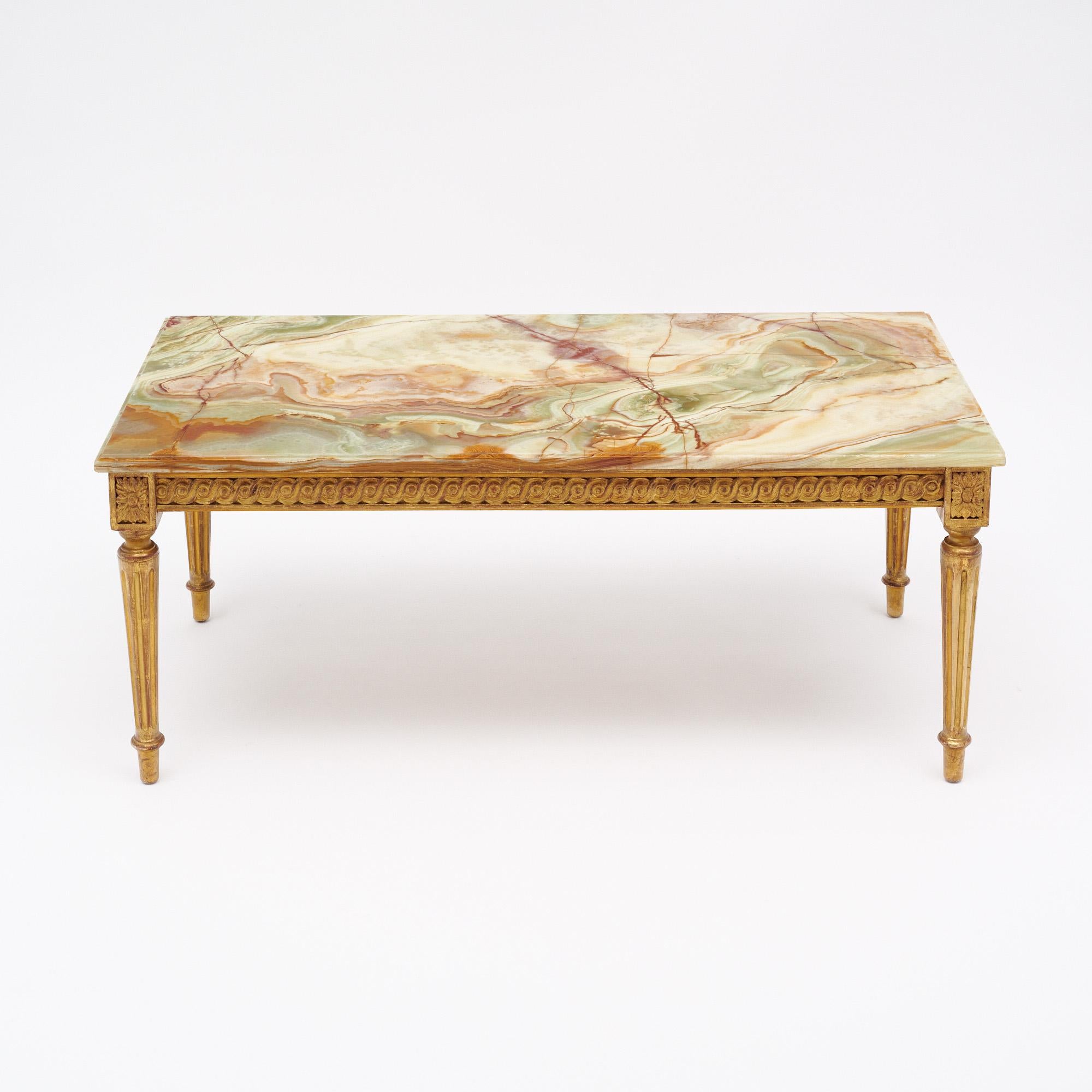 French coffee table in the Louis XVI style. The professionally restored onyx marble top sits on a finely hand carved and gold leafed wooden base. This piece is in very nice vintage condition with only minor surface wear consistent with age and use.