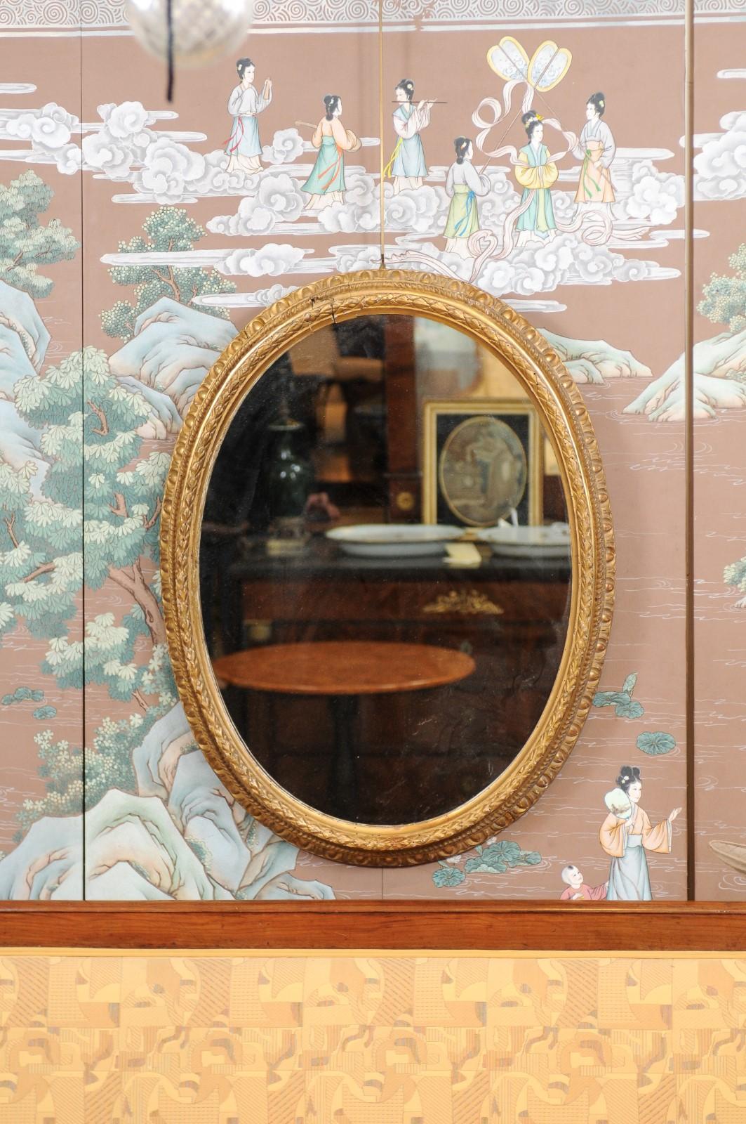 A Louis XVI oval giltwood mirror with egg-and-dart, roping and laurel foliage detail on mirror frame. The mirror dating from the late 18th century.