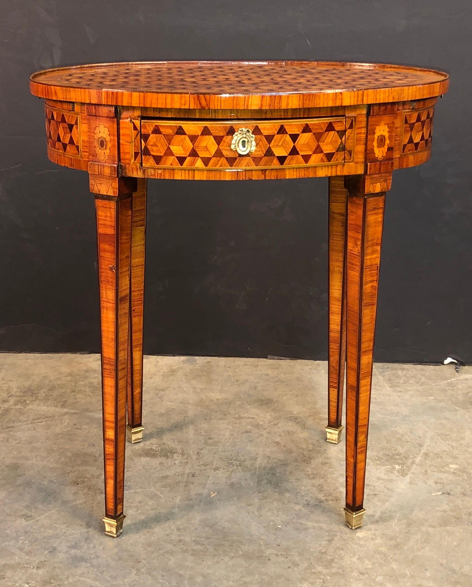 A fine French Louis XVI oval parquetry inlaid side table with a wooden gallery, single central drawer with two leather inset top candle slides, with bronze mounts and square tapered legs.
