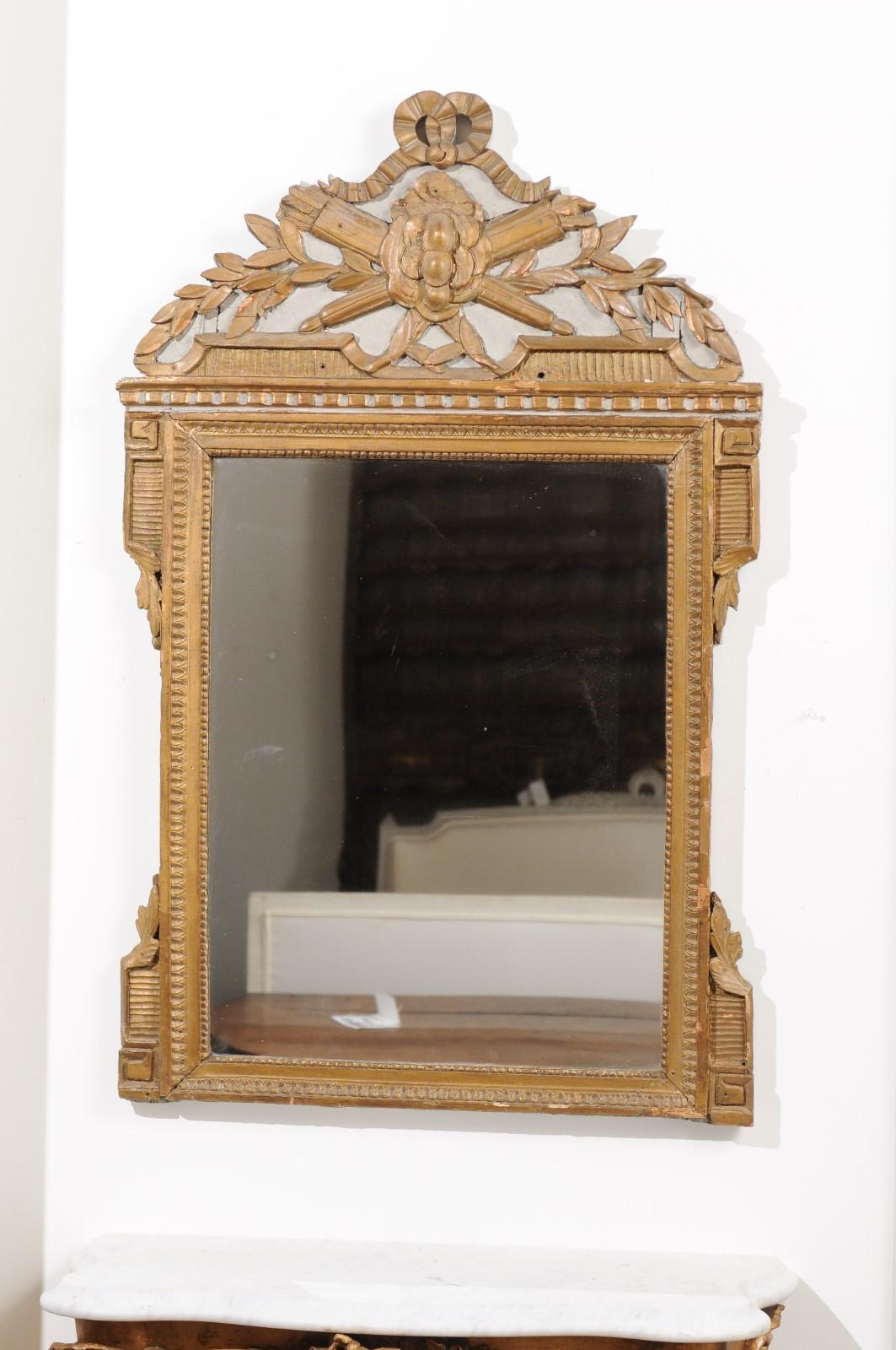 A French Louis XVI period painted and gilded wall mirror from the second half of the 18th century, with quiver and arrow motifs. Born in France during the early years of King Louis XVI's reign, this exquisite wall mirror attracts our attention with