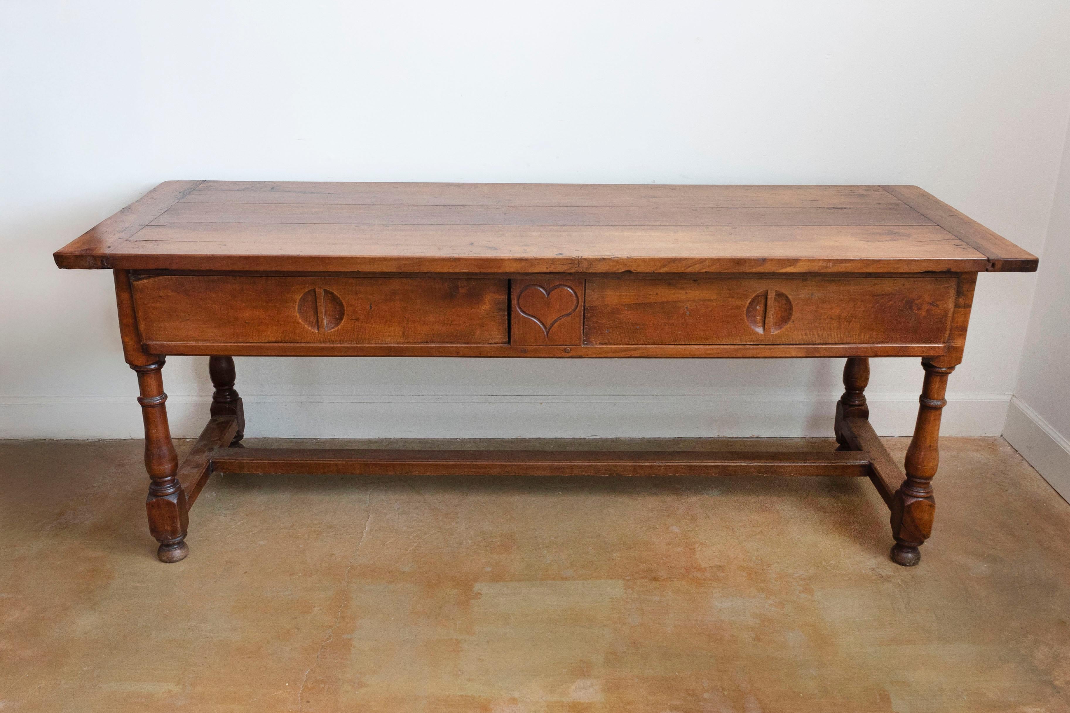 Table de ferme en bois d'époque Louis XVI de la fin du XVIIIe siècle, avec panneaux coulissants, cœur sculpté, pieds tournés et traverse en forme de H. Créée en France dans le dernier quart du XVIIIe siècle, cette table de ferme en bois présente un
