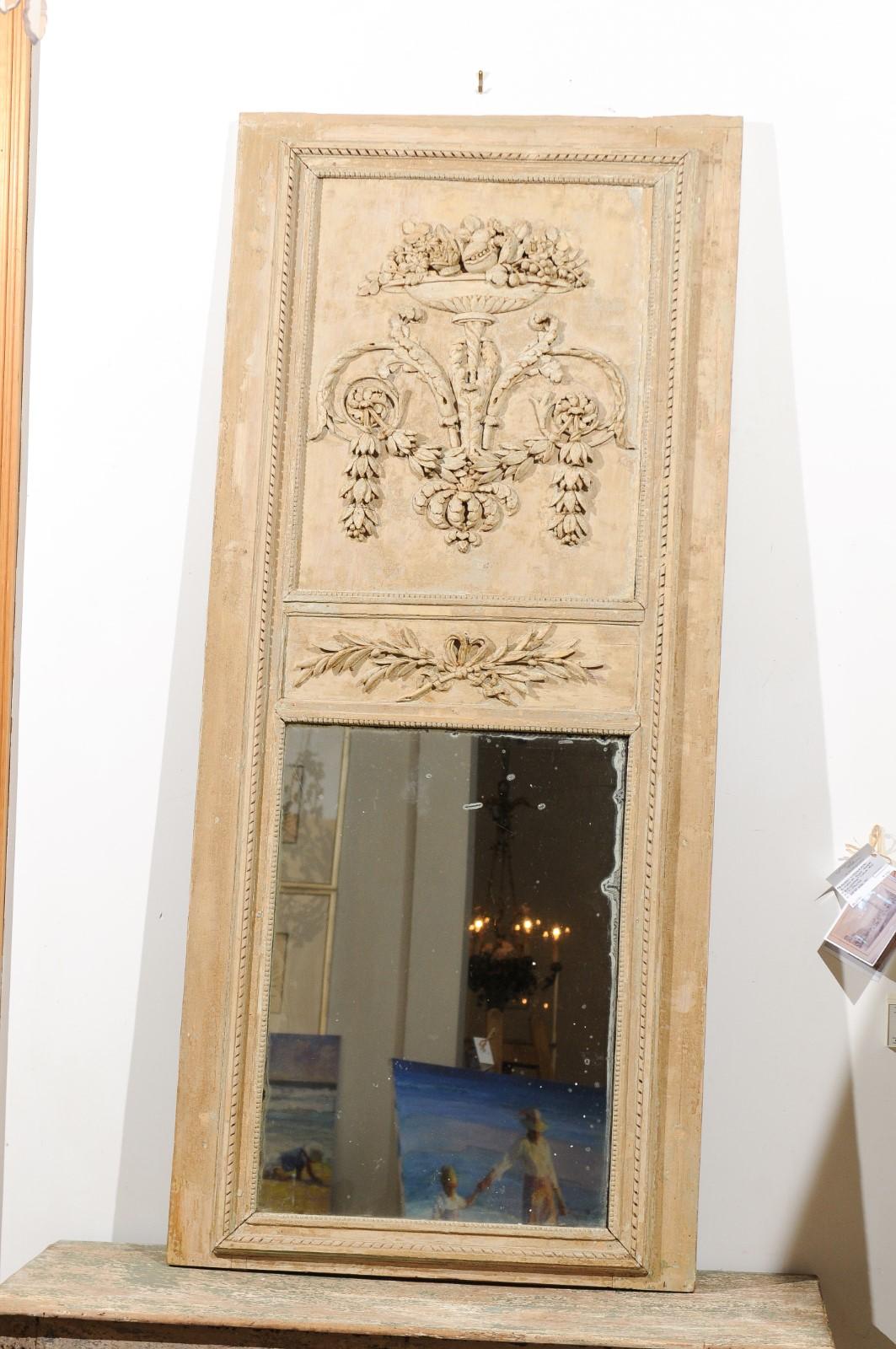 A French painted wood Louis XVI period trumeau mirror from the late 18th century, with foliage, scrollwork and urn motifs. Born in France at the end of the Age of Enlightenment, this Louis XVI trumeau mirror features a linear Silhouette, beautifully