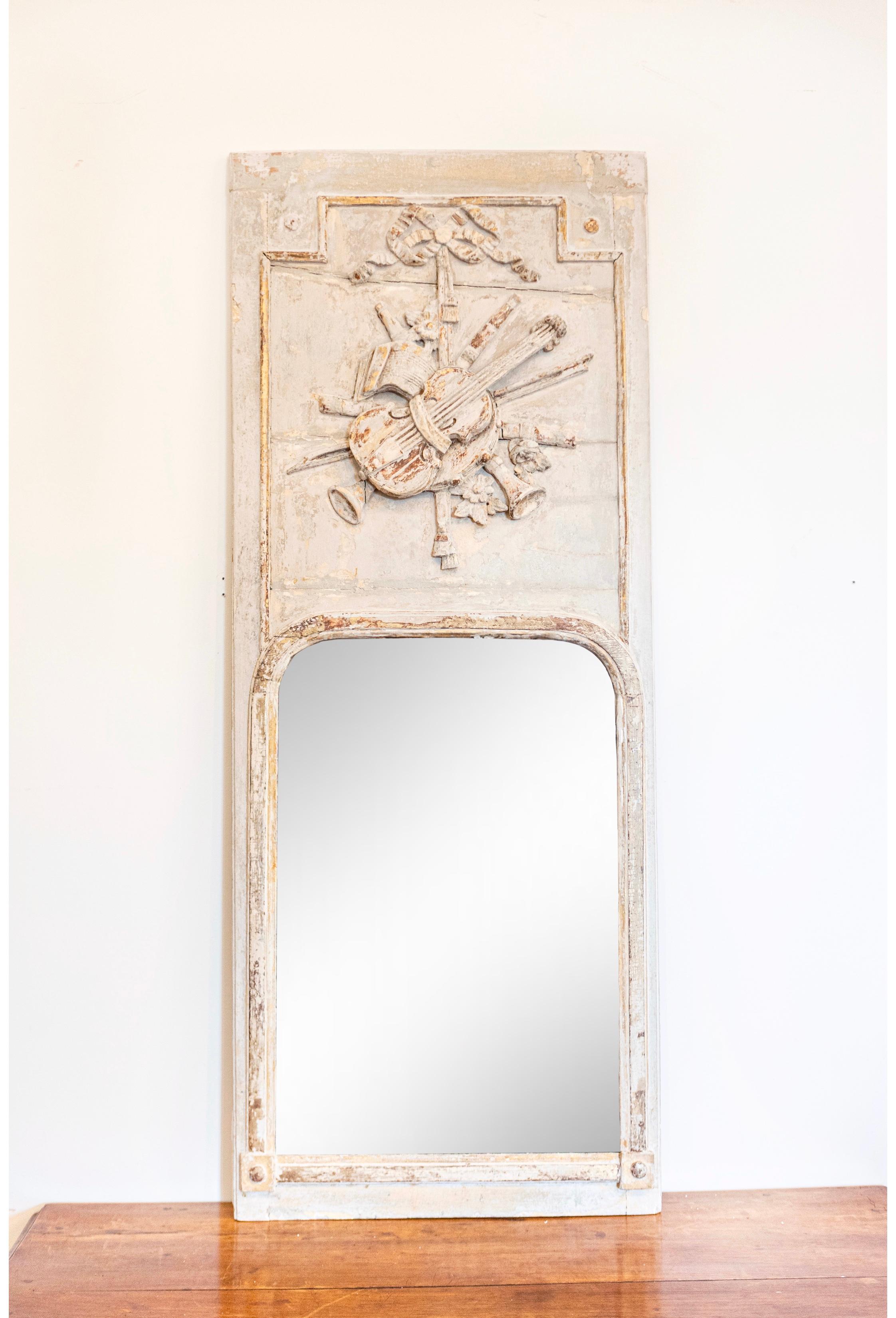 A French Louis XVI period trumeau mirror from circa 1790 with carved Liberal Arts Allegory, antique off white painted finish and gilt accents. This captivating French Louis XVI period trumeau mirror, dating back to circa 1790, is an emblem of