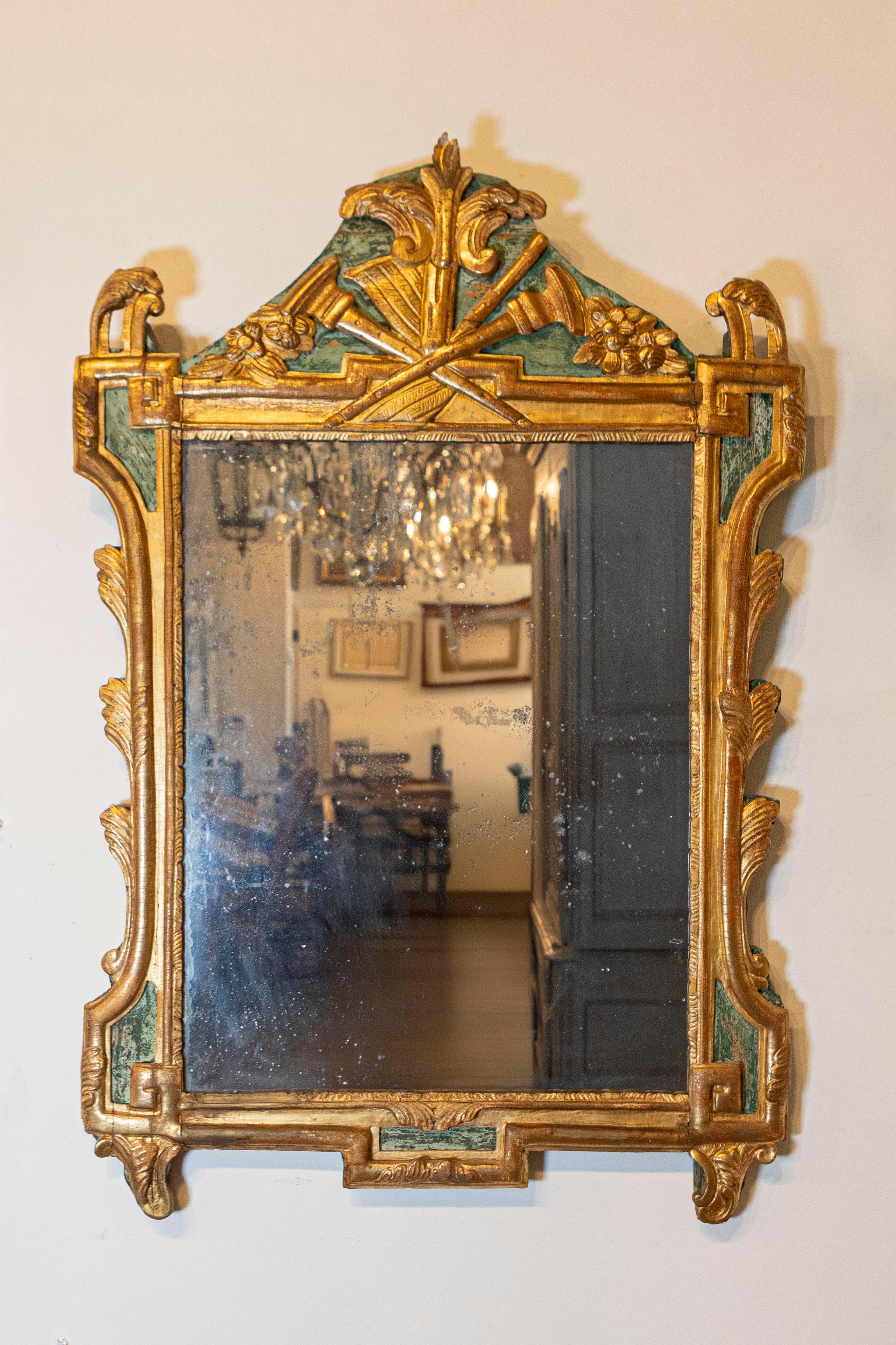 Miroir en bois peint et doré d'époque Louis XVI (XVIIIe siècle), sculpté d'une allégorie des arts libéraux symbolisée par des instruments de musique et des partitions. Ce miroir d'époque Louis XVI français du XVIIIe siècle est un splendide artefact