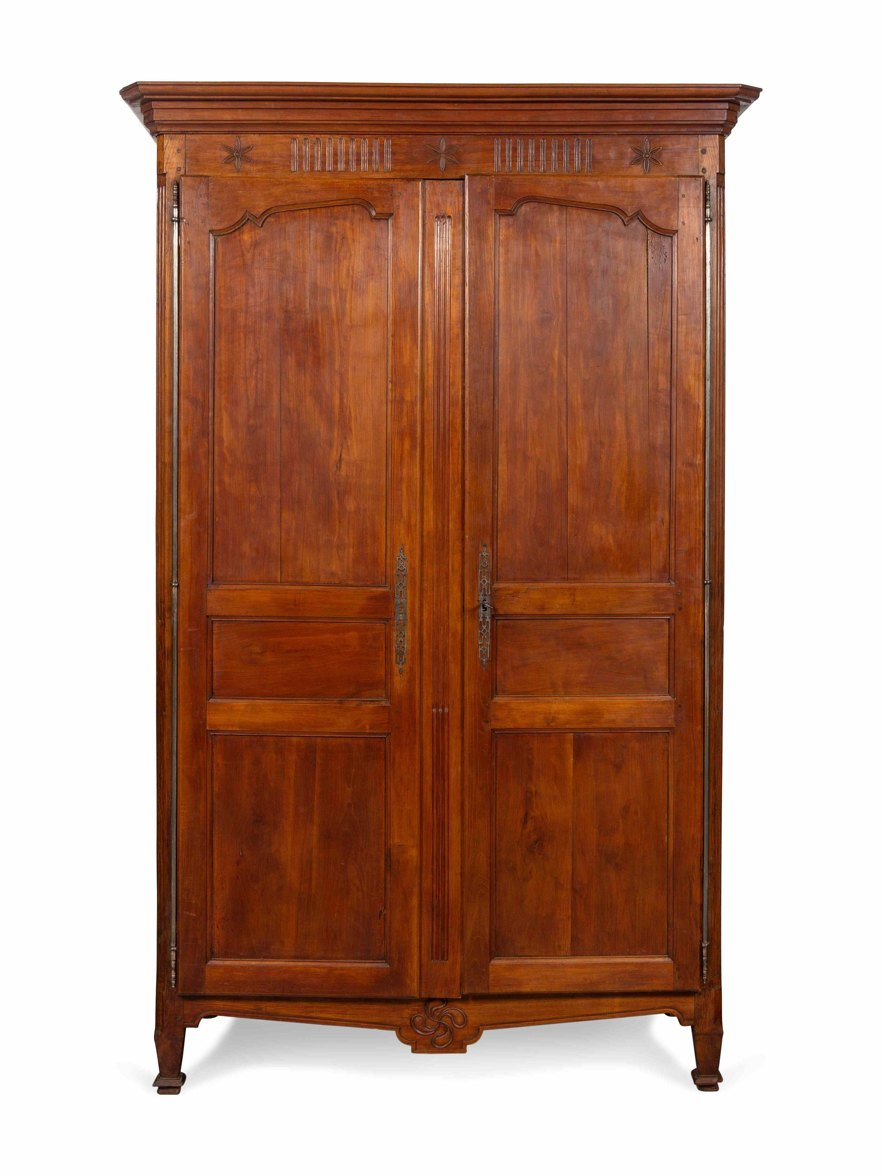 A nice Louis XVI period armoire in walnut, with carved panels above and below the doors, fluted posts flanking each door, and a nicely fitted interior with lower cabinet doors. The interior has three shelves in theupper case and one in the lower