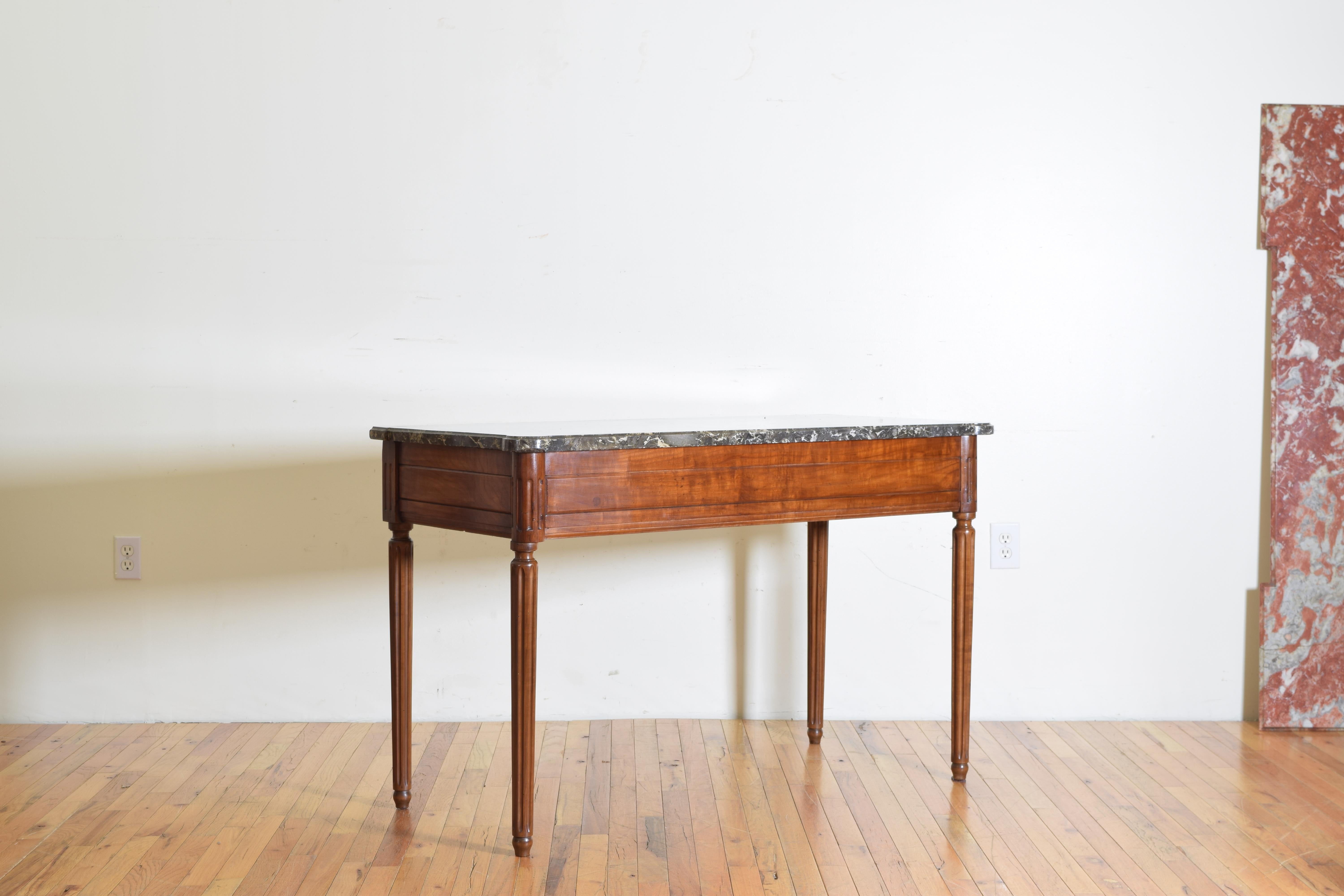 Having a shaped thick marble top with rounded front corners and notched rear corners, the frame having fluted corners and round tapering fluted legs, the panel with rectangular carvings.