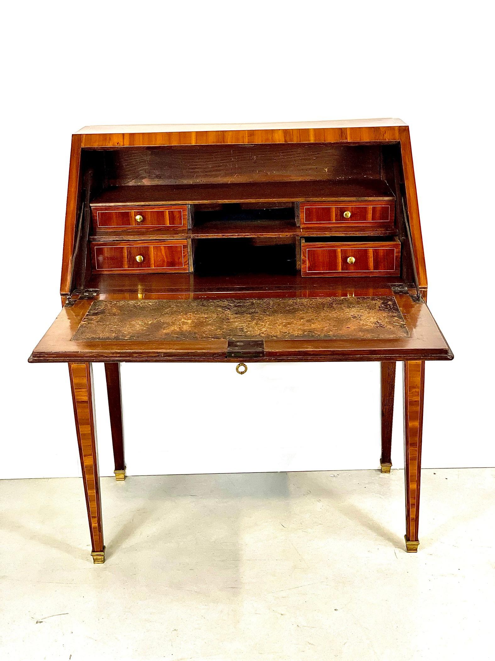 This elegant writing desk, known quirkily as a “bureau à dos d’âne” (donkey’s back desk), is beautifully veneered in rosewood, including reverse diamonds and butterfly-wings, which are typical of the Louis XVI period. 
The desk is opened by a