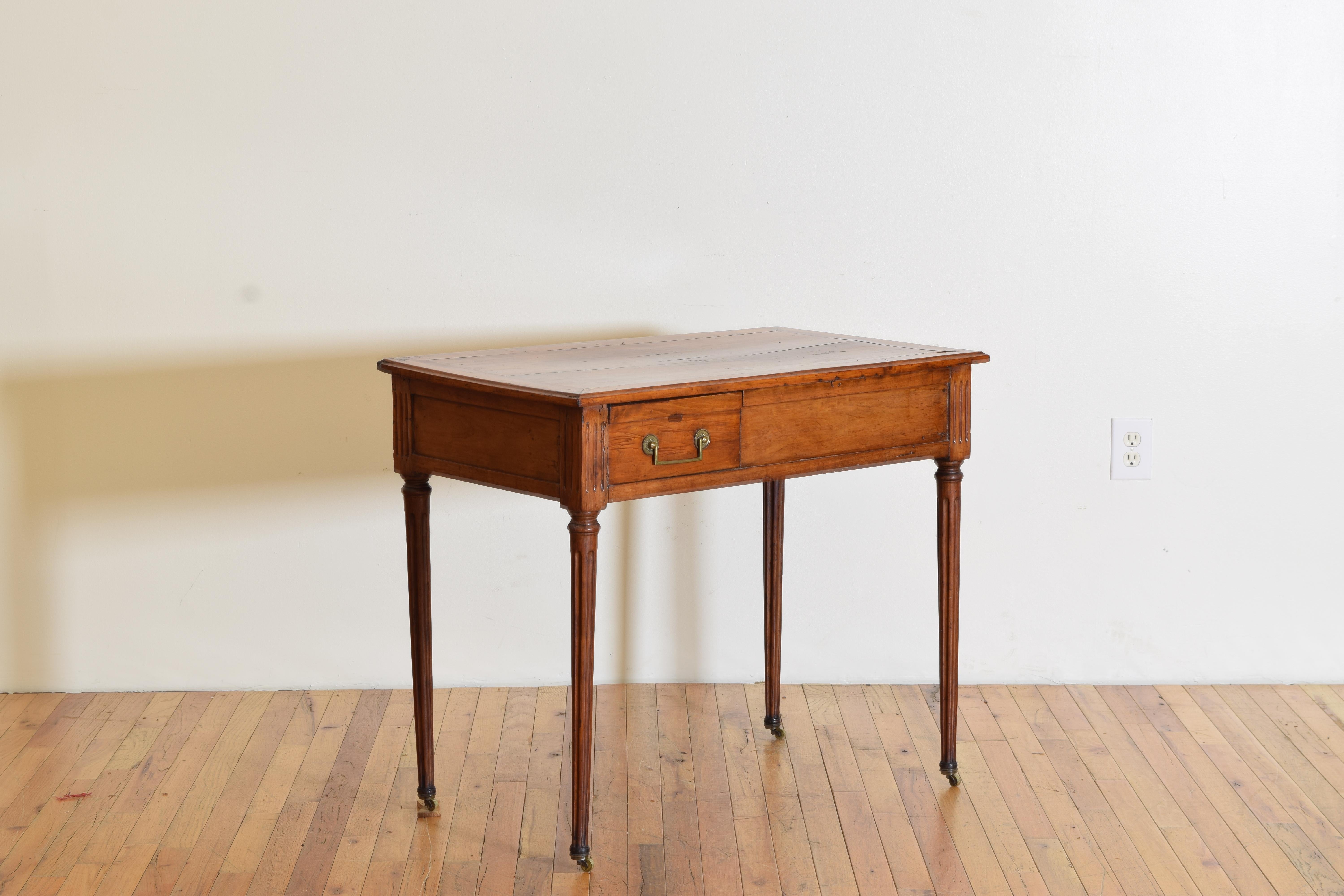Having a rectangular top above a conforming case housing an off center drawer as well as a side drawer, both with brass handles, raised on circular and fluted tapering legs, retaining original brass casters