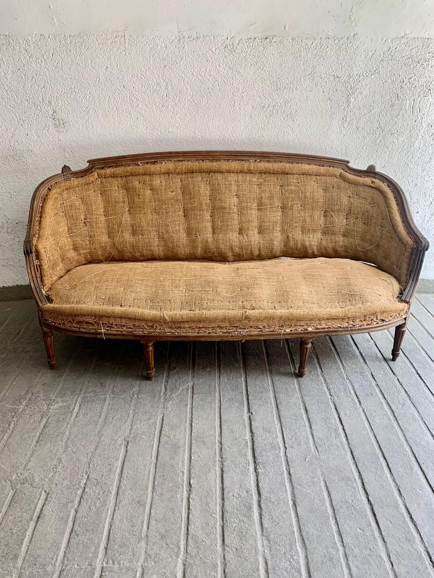 Ein Louis XVI-Sofa aus geschnitzter Nussbaum-Corbeille aus dem späten 18. Jahrhundert, mit einer leicht umhüllenden Rückenlehne, die für diese Zeit charakteristisch ist, gekrönt von einigen floralen Zacken. Dieses im letzten Viertel des 18.