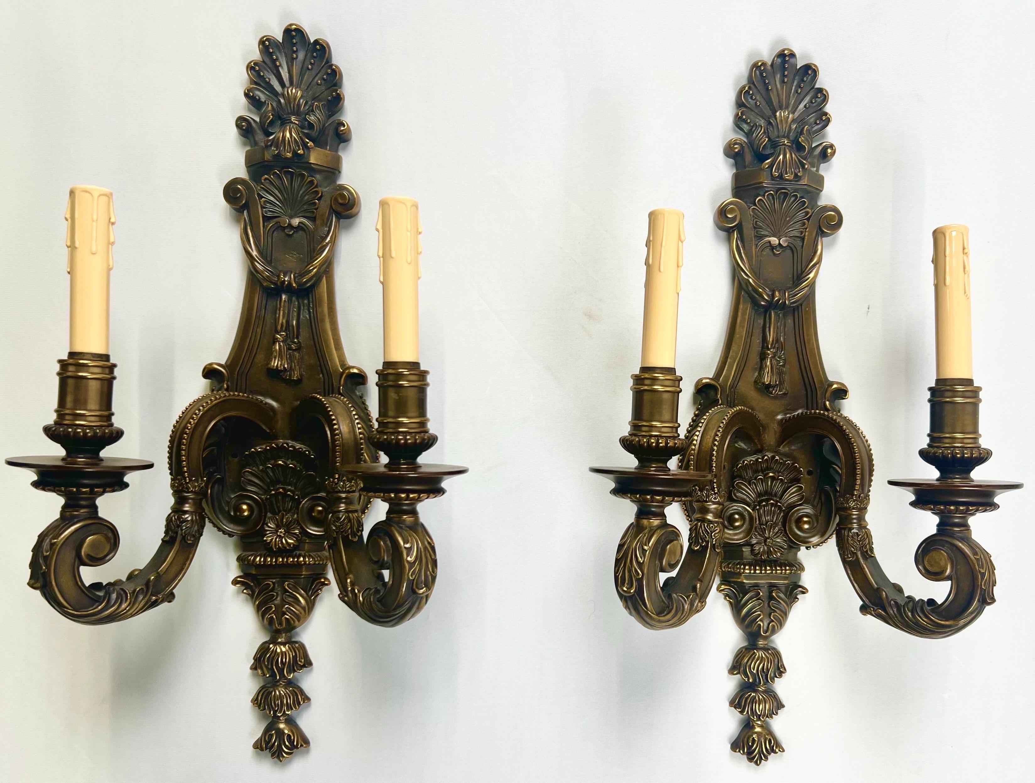 Pair of French Louis XVI Revival Style Patinated Bronze Two-Arm Wall Sconces: 

A distinguished pair of French Louis XVI Revival wall sconces, expertly cast in patinated bronze and richly adorned with classical motifs. Each sconce features two