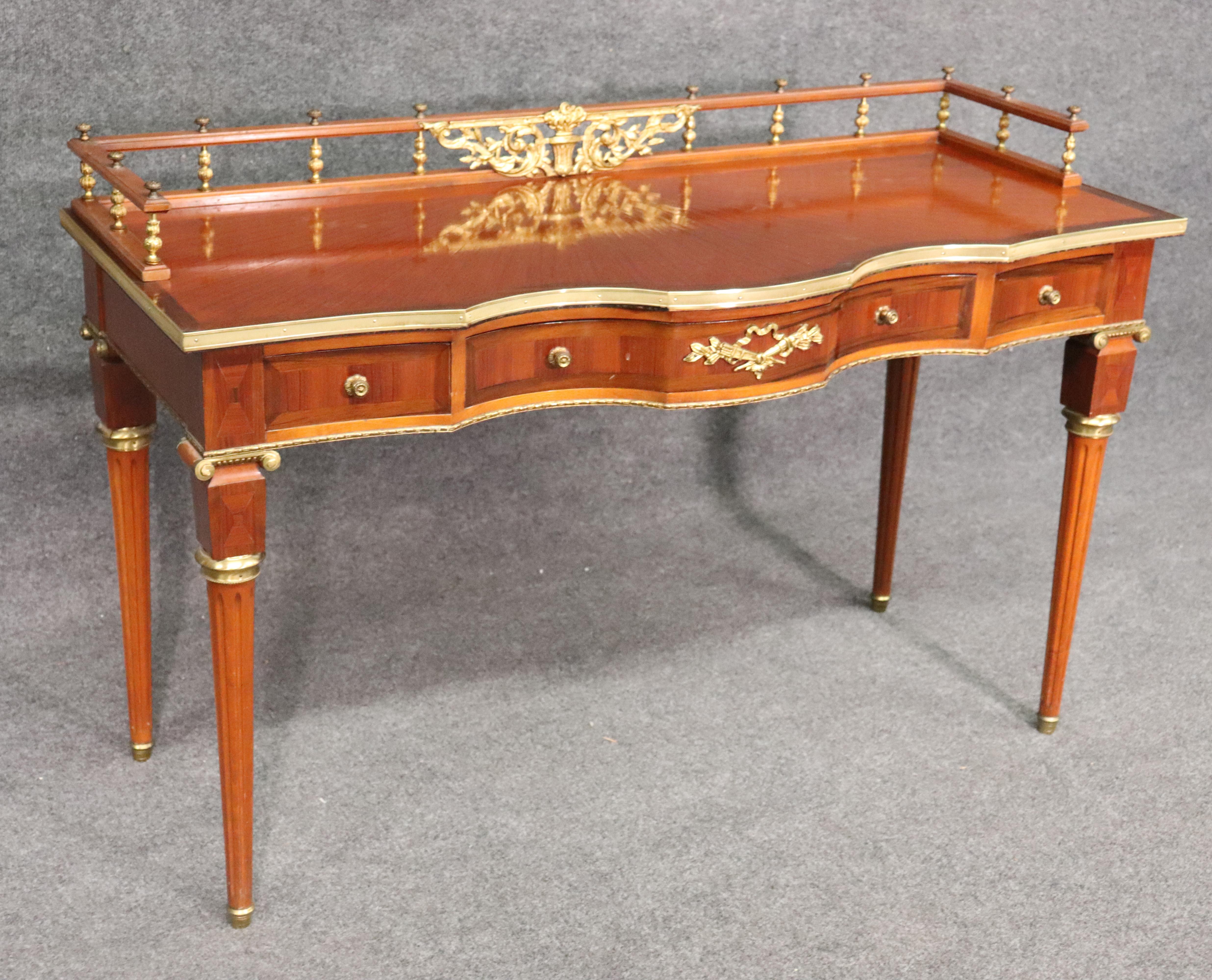 This is a fantastic writing table with gilded bronze ormolu and fantastic satinwood. The desk has a beautiful gallery that surrounds the top and is in very good condition for its age. The desk measures 50 wide x 33 tall to the top of the gallery and