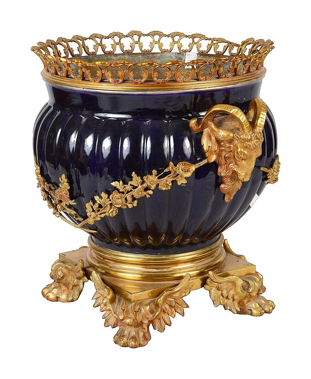 A striking late 19th Century French Louis XVI Sevres style cobalt blue and gilded ormolu jardiniere, with a pierced gallery, Rams head handles to either side, united by garlands of flowers and raised on winged paw feet.

Batch 76 cdowns BUEZZ