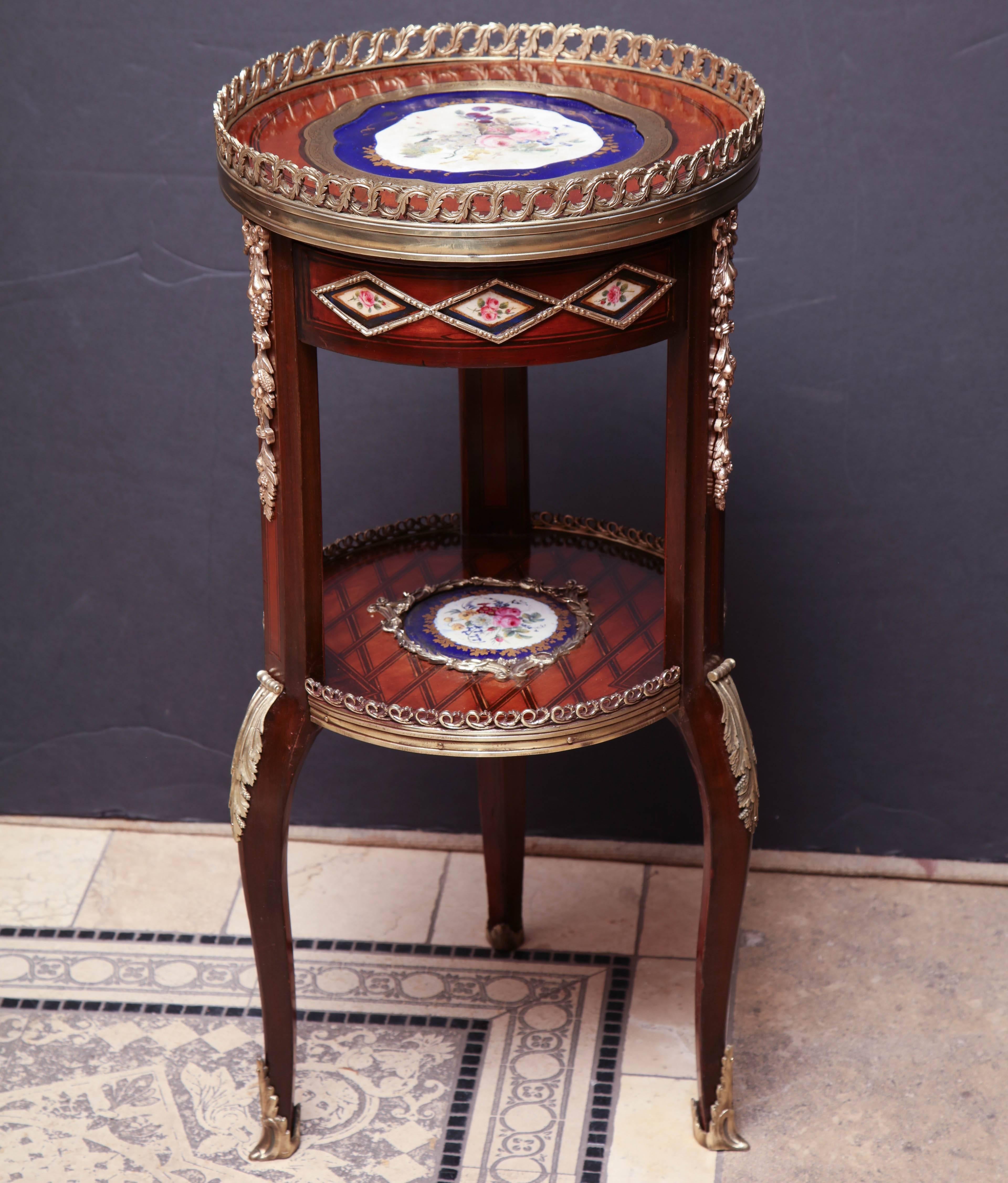 A fine French Louis XVI round side table with porcelain mounts, pierced bronze gallery and mounts, marquetry inlaid lower shelf with bronze ormolu sabots.