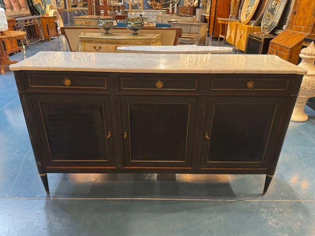 Vintage French Louis XVI design black painted sideboard with brass trim and Carrara marble. Circa 1940. These sideboards are perfect for adding gravitas to a room—whether you're going full Versailles or mixing old-world charm with contemporary art.