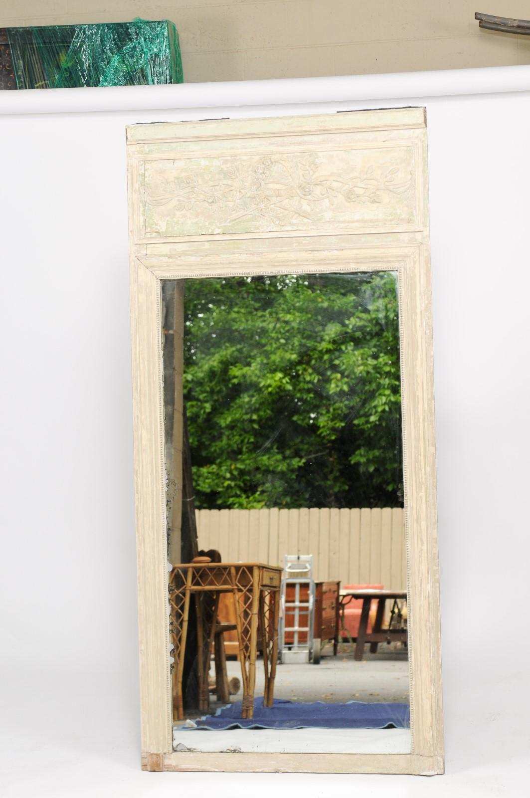 A French Louis XVI style painted trumeau mirror from the mid-19th century, with original mercury glass, weathered patina and foliage décor. From an apartment in Paris, a 19th century trumeau mirror that has all the age and patina that makes it