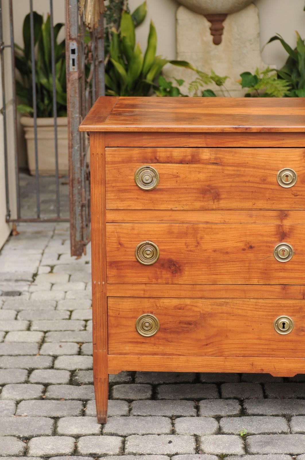 A French Louis XVI style walnut three-drawer commode from the mid-19th century, with butterfly veneer, fluted side posts and tapered feet. Born under the reign of France's last king Louis-Philippe, this walnut commode features a rectangular planked