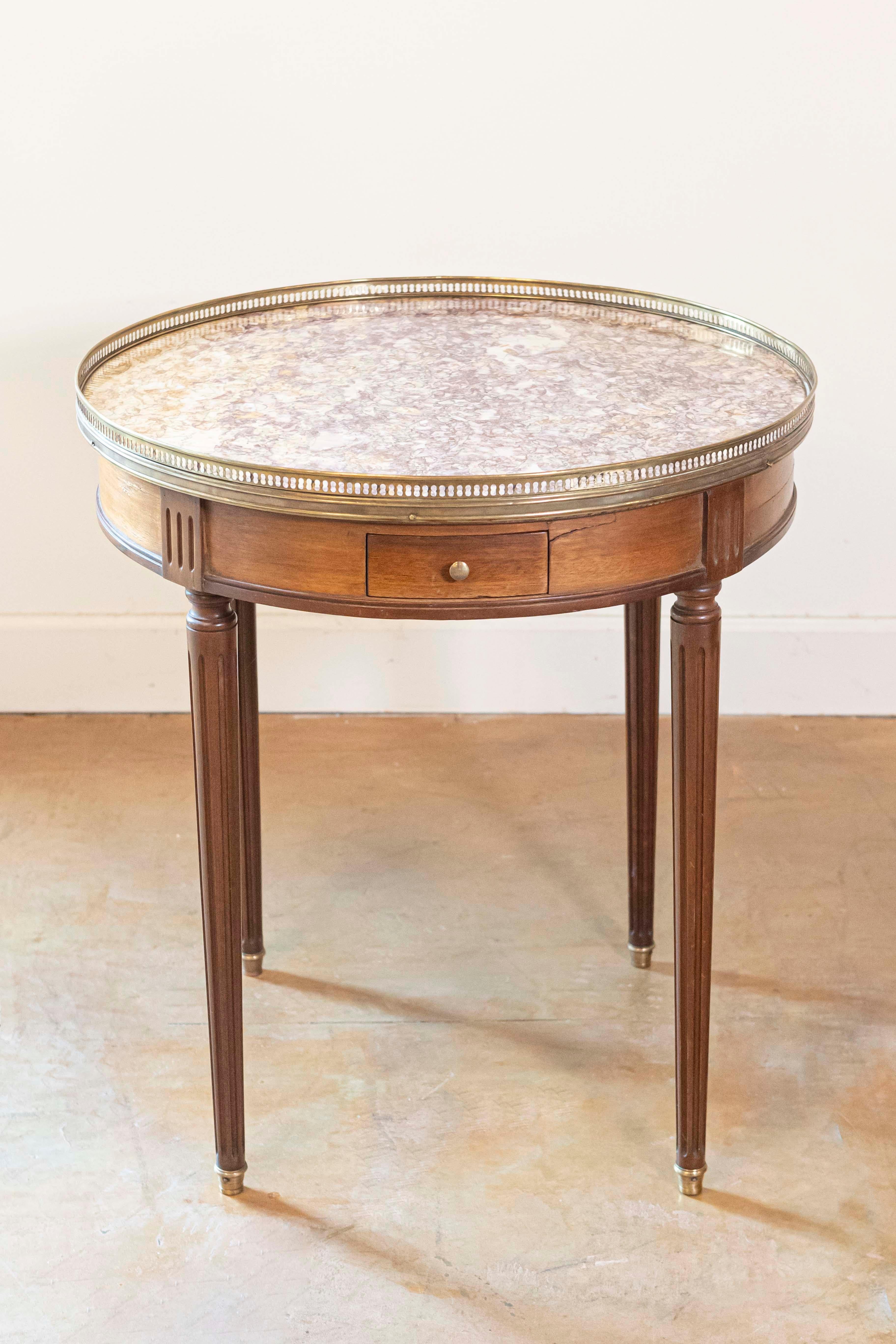 Mesa bouillotte francesa de estilo Luis XVI de finales del siglo XIX, con tablero de mármol incrustado, galería de latón, cajones y patas estriadas. Nacida en Francia durante los últimos años del siglo XIX, esta encantadora mesa bouillotte presenta
