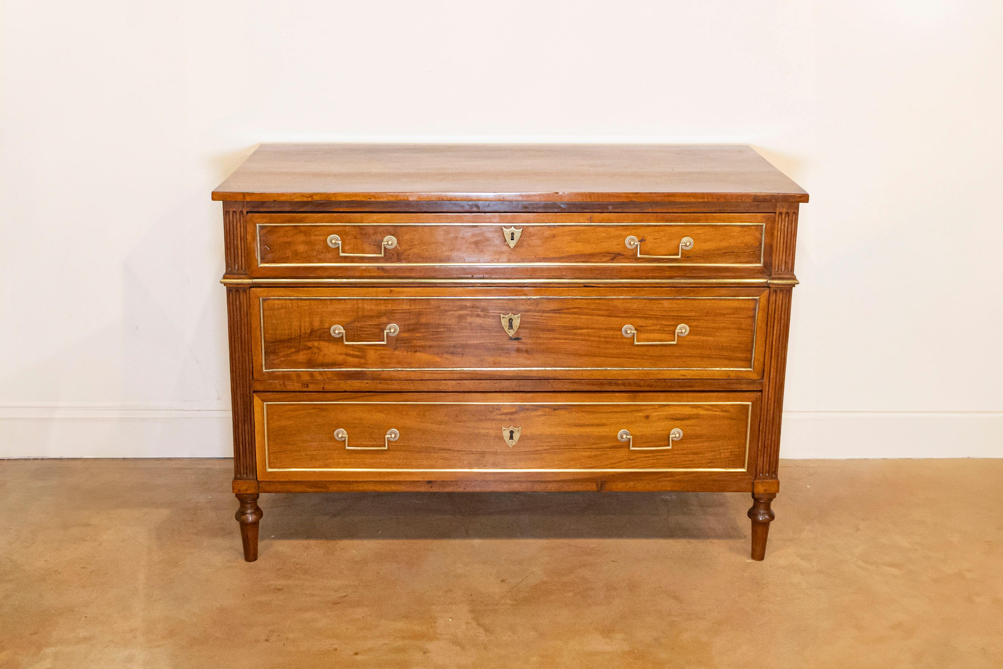 Una commode francese in legno in stile Luigi XVI della fine del XIX secolo, con accenti in ottone. Creata in Francia durante l'ultimo decennio del XIX secolo, questa commode presenta un piano rettangolare che si trova al di sopra di tre cassetti
