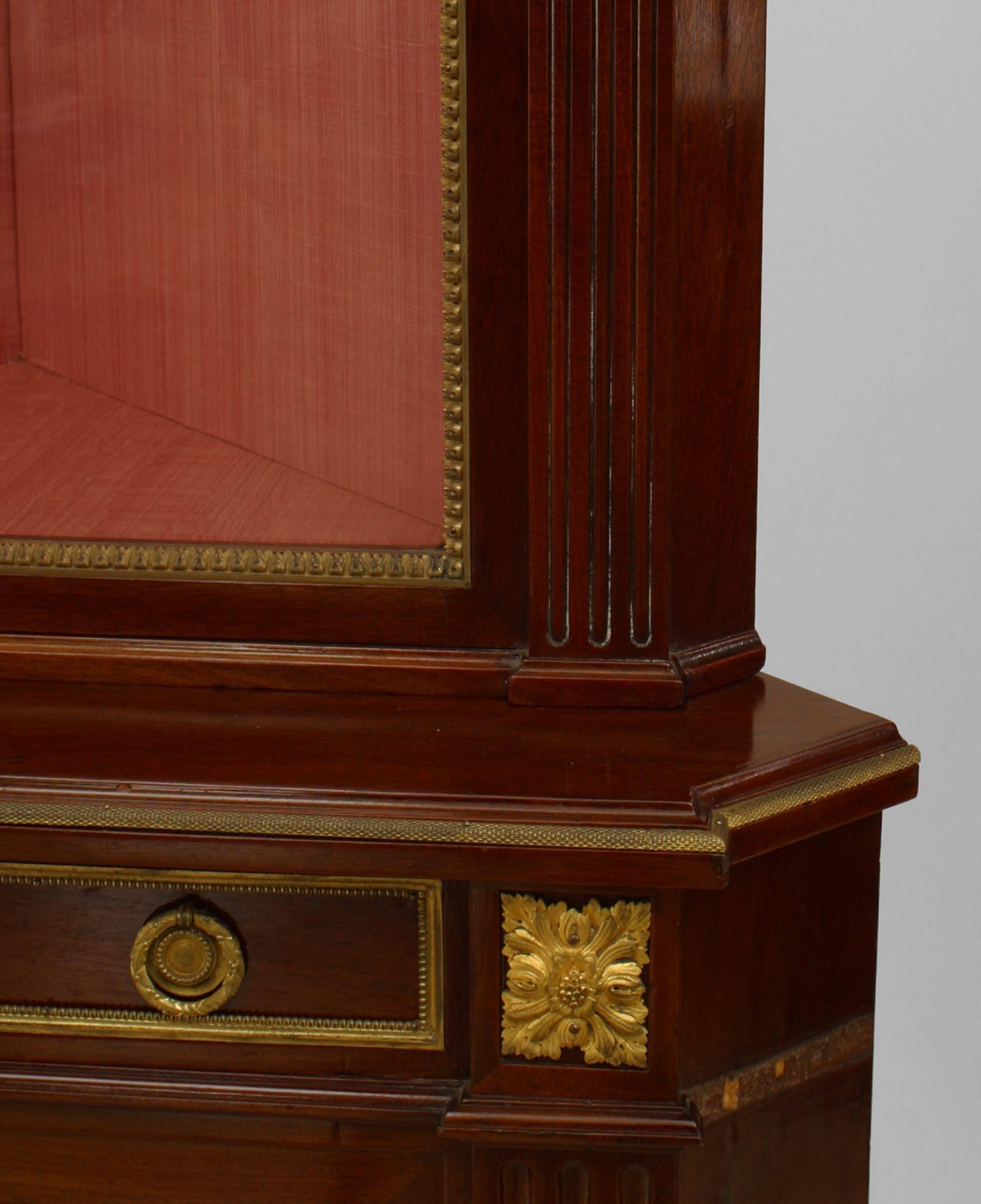 French Louis XVI-style (19th Century) mahogany 2 section corner cabinet with gilt bronze trim and a glass door upper section and a lower section with a drawer and brass grill door
