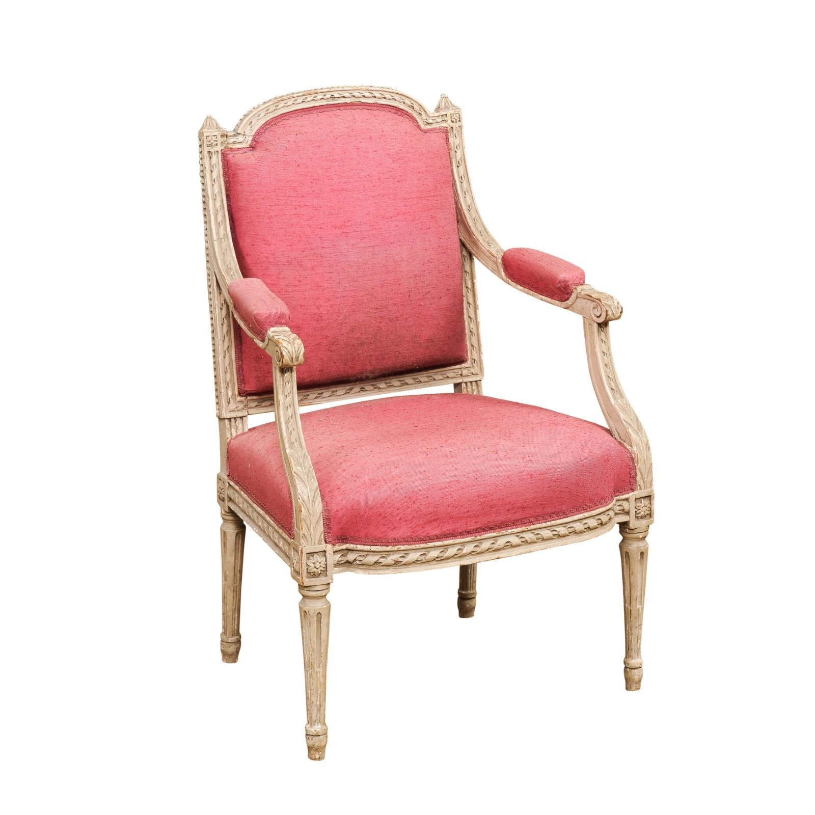 A French Louis XVI style painted wood armchair from the 19th century with carved décor including twisted rope motifs, acanthus leaves, rosettes and petite beads. Step into the era of French elegance with this 19th-century Louis XVI style painted
