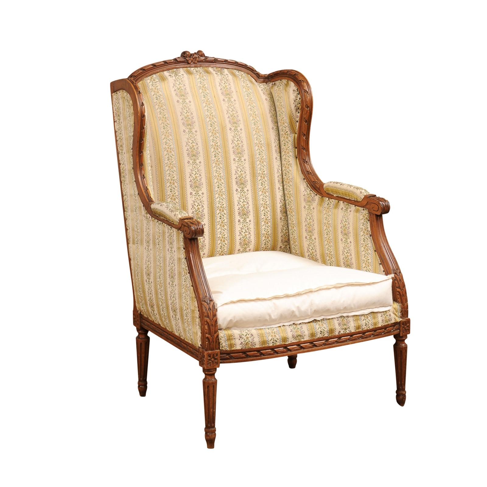 A French Louis XVI style walnut bergère wingback armchair from the 19th century with carved twisted ribbon, roses and foliage motifs. This French Louis XVI style walnut bergère wingback armchair, hailing from the 19th century, is a true testament to