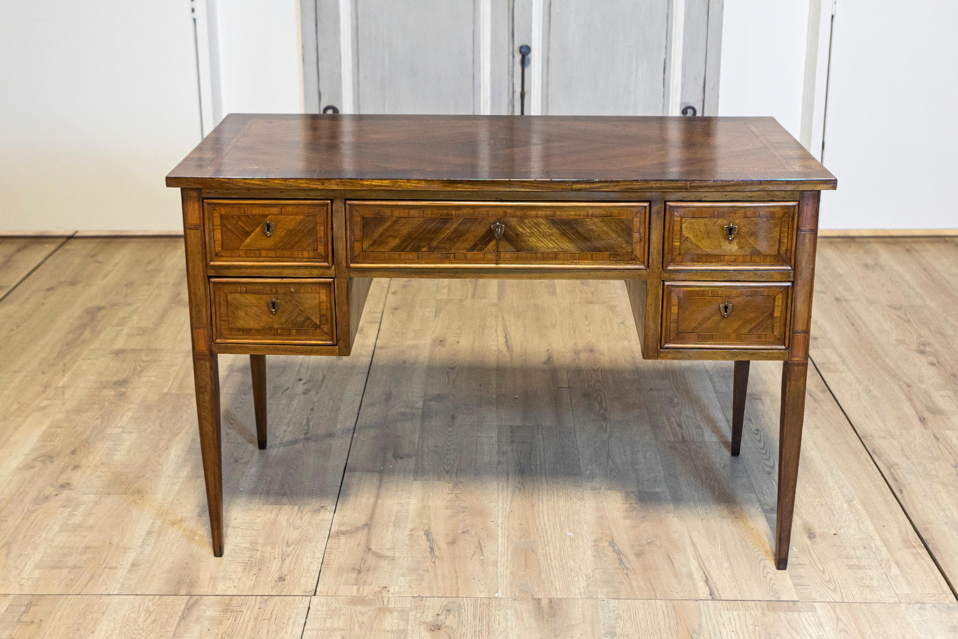 Ein italienischer Nussbaumschreibtisch im Louis-XVI-Stil aus dem 19. Jahrhundert mit fünf Schubladen, Kreuzbandintarsien, floralen Einlegearbeiten und konischen Beinen. Dieser exquisite Schreibtisch aus Nussbaum im italienischen Louis-XVI-Stil aus