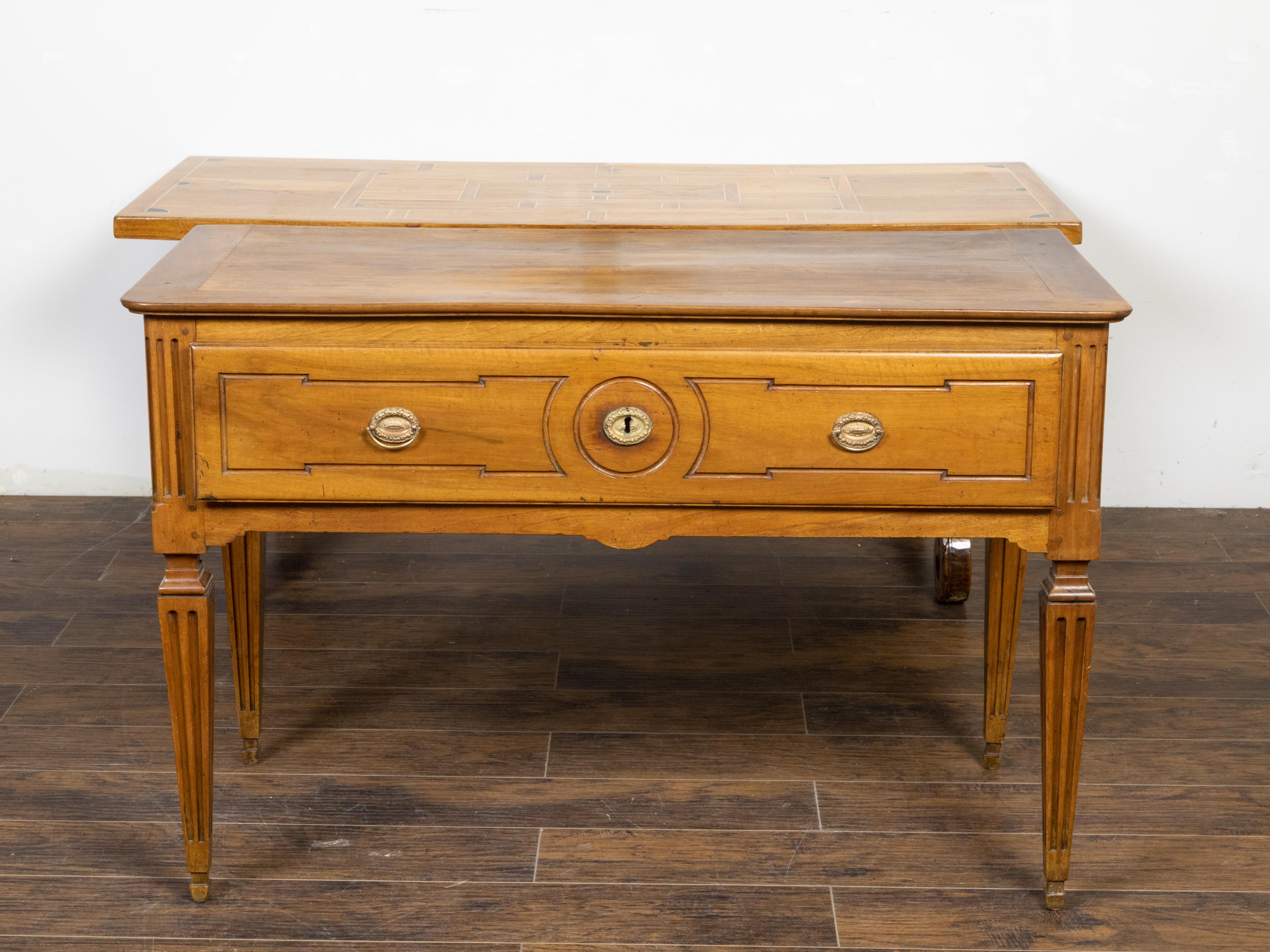 A French Louis XVI style walnut console table from the 19th century, with large single drawer, carved geometric motifs, tapered legs and fluted accents. Created in France during the 19th century, this walnut table showcases the stylistic