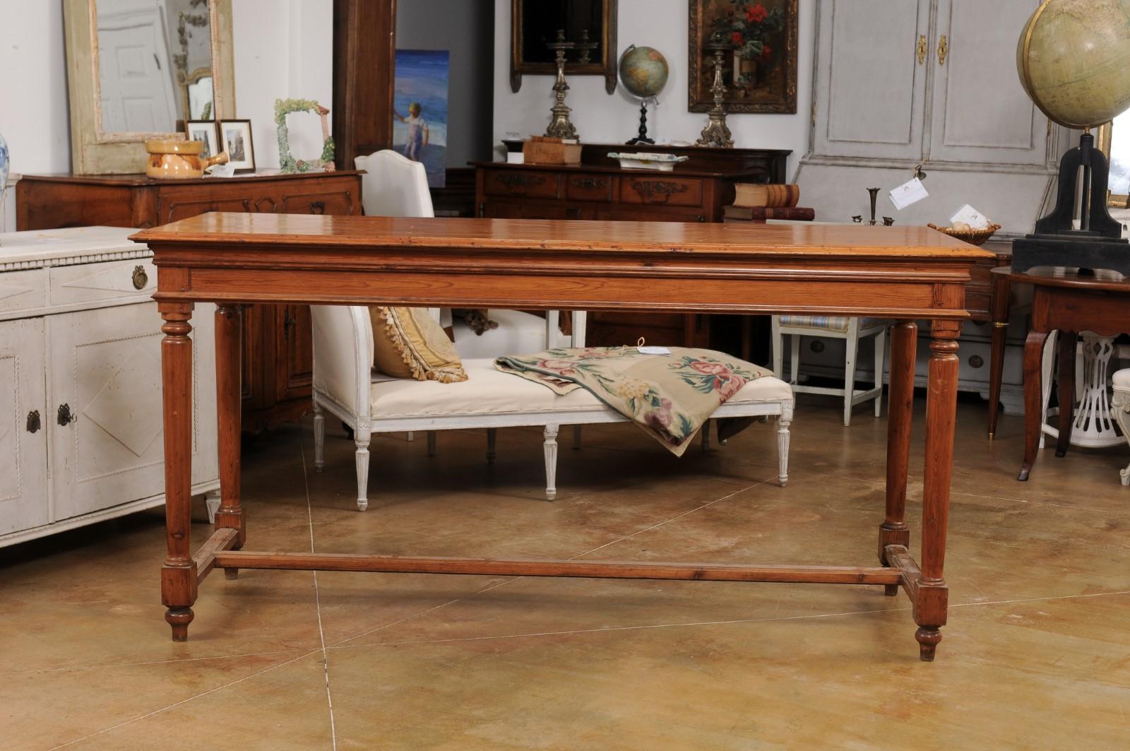 A French Louis XVI style high bar pine table from the 20th century, with cylindrical tapering legs, toupie feet and H-Form cross stretcher. Created in France during the 20th century, this pine bar table showcases the stylistic characteristics of the
