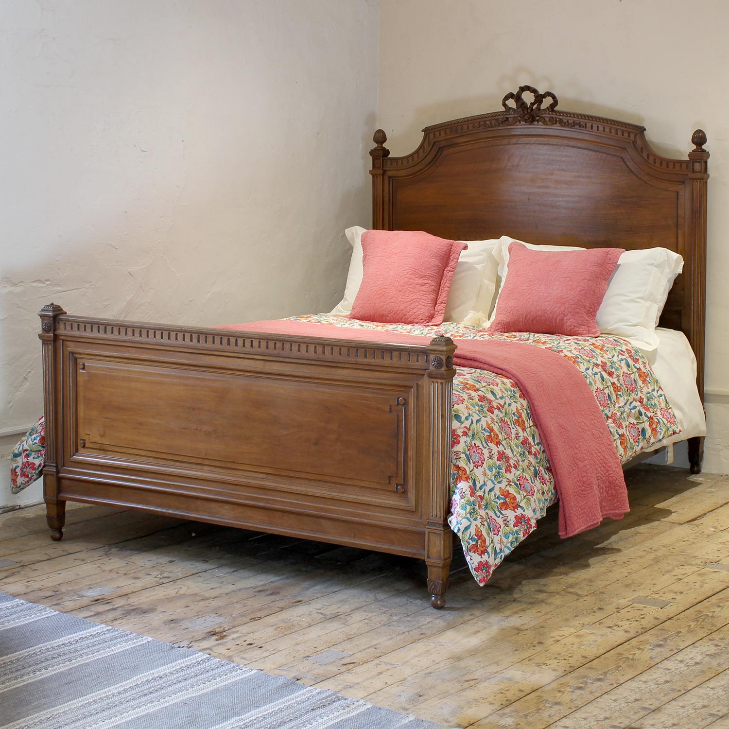 An attractive French Louis XVI style antique bed in walnut with square column fluted posts, carved finials and bow ribbon carved pediment. 

This bed accepts a European King, 5ft 3in (63 in) or 160cm wide, base and mattress set.

The price includes