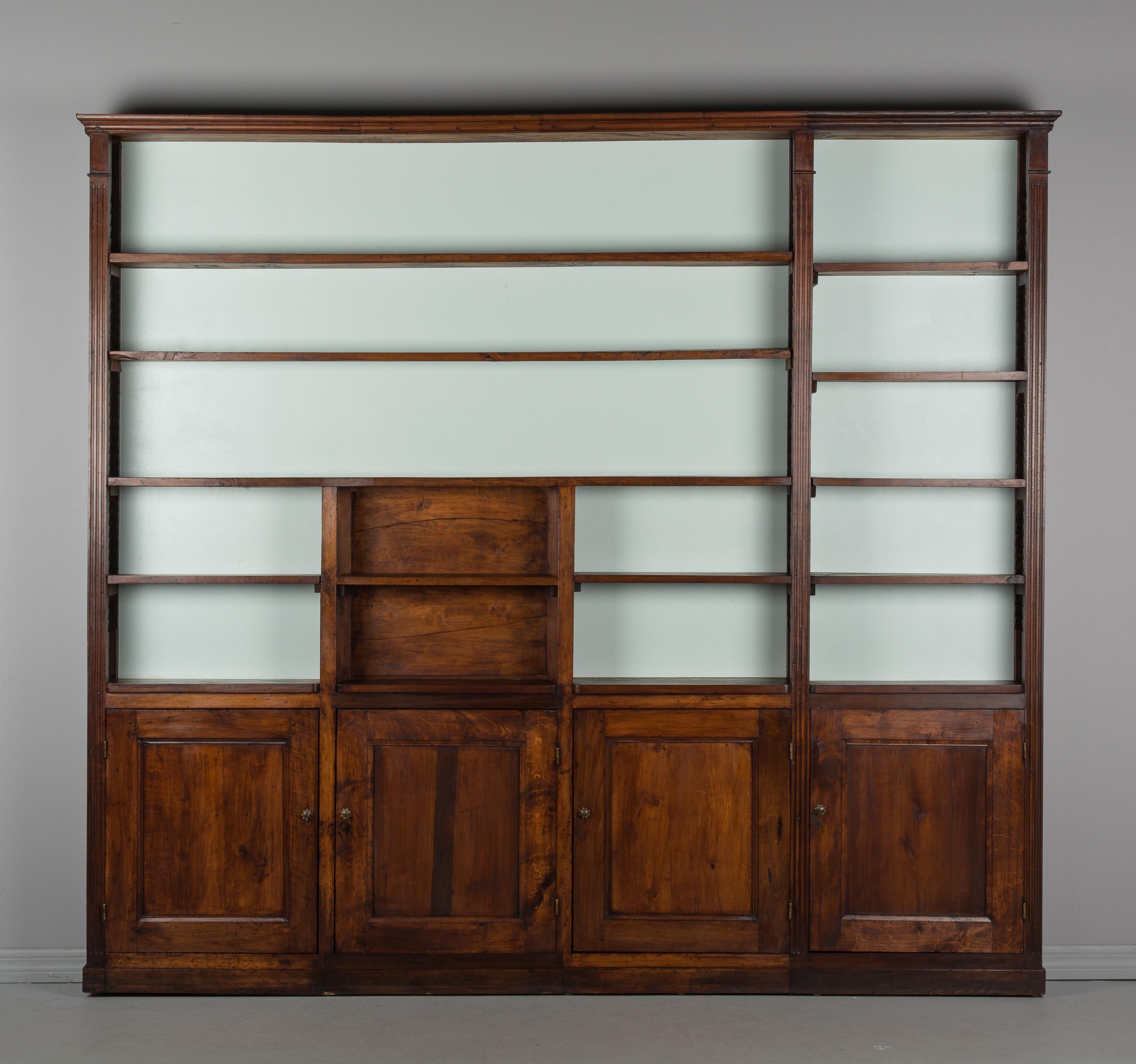 An early 20th century Louis XVI style large, shallow shelving unit from an apothecary in France. Made of solid walnut with waxed finish. Beautiful character and patina of the wood with knots and splits and old worm holes. Very versatile with several