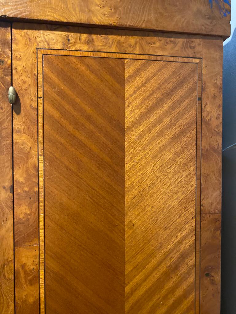 Antique French Louis XVI style walnut 3-door armoire wardrobe cabinet, circa 1900. Brass flower crown to the front. Marquetry work on both doors depicting flower baskets with banding to the front and side panels. Bow fronted, mirror door center