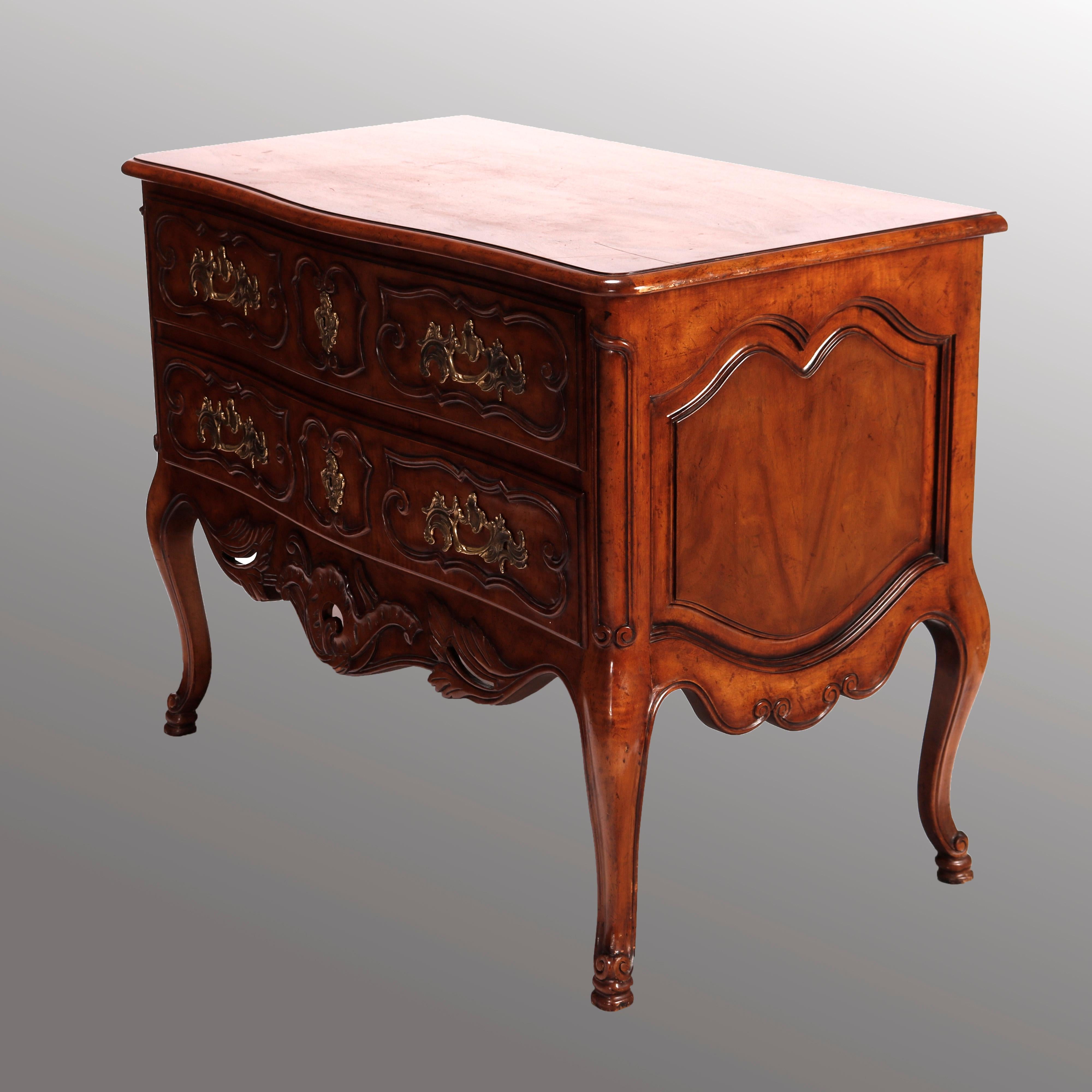 A French Louis XVI style commode by Baker of the McMillen Collection offers walnut construction with shaped and beveled top surmounting case with two drawers and having carved scroll, foliate and gadroon decoration, raised on cabriole legs with