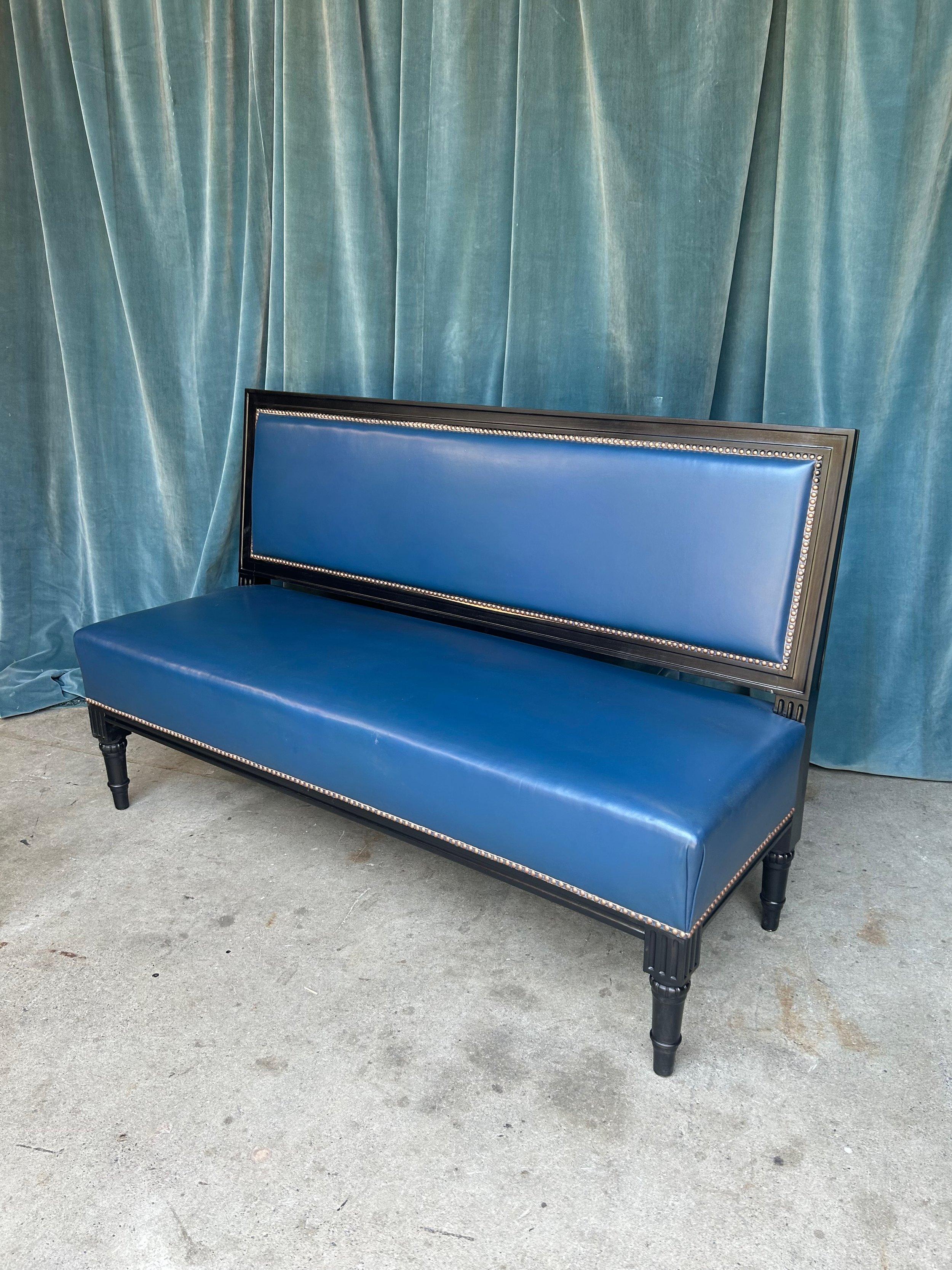 A classic French early 20th century ebonized banquette upholstered in blue leather. Discover the allure of French elegance with this handsome early 20th century ebonized banquette, upholstered in sumptuous deep blue leather. This exquisite piece